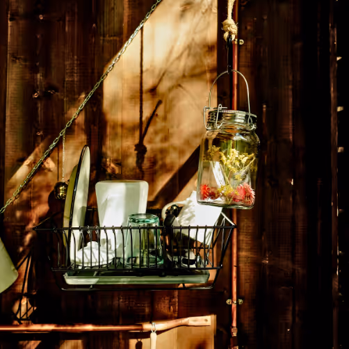 Drying dishes in the kitchen of a cabin in the woods, alongside a solar lamp