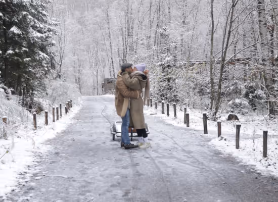 A cute couple on a romantic weekend kissing in the snow at Forest Village Les Ardennes