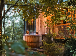 A couple is enjoying a dip in the hot tub of their Nutchel cabin in the woods with jacuzzi