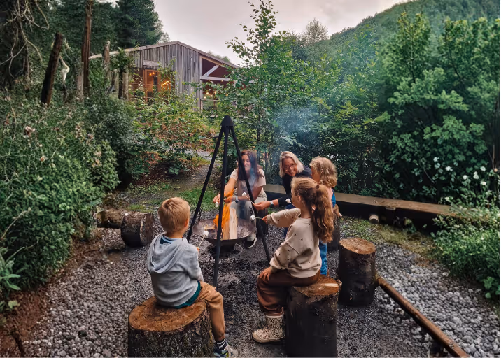 Eltern, die während ihres Urlaubs mit den Kindern inCosy Cabins Nutchel Cosy Cabins Marshmallows über dem Lagerfeuer schmelzen lassen