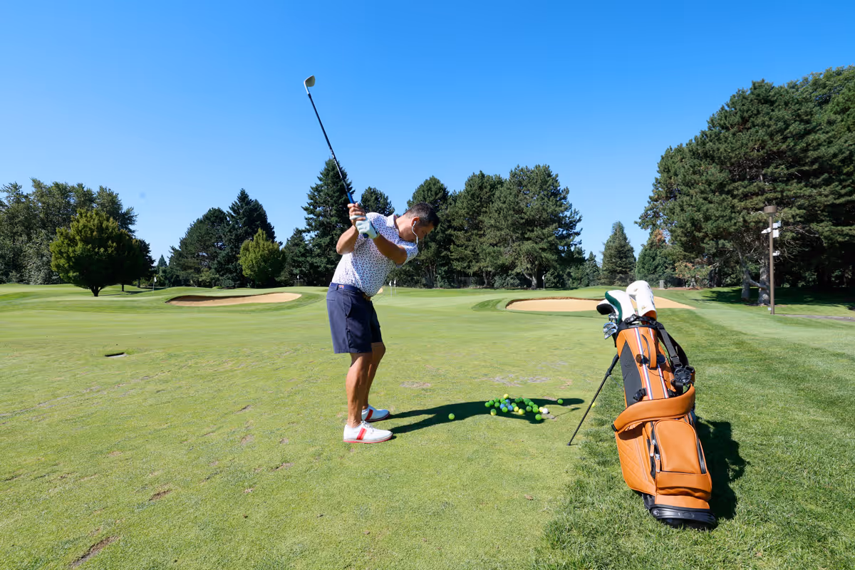 Male golfer taking practice swings on the Mason Course