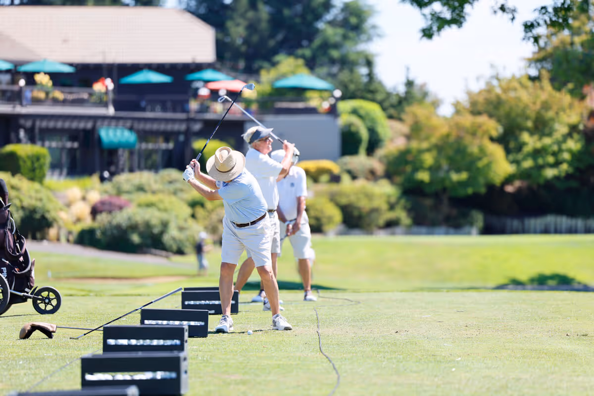 Line of golfers taking swings on the driving range