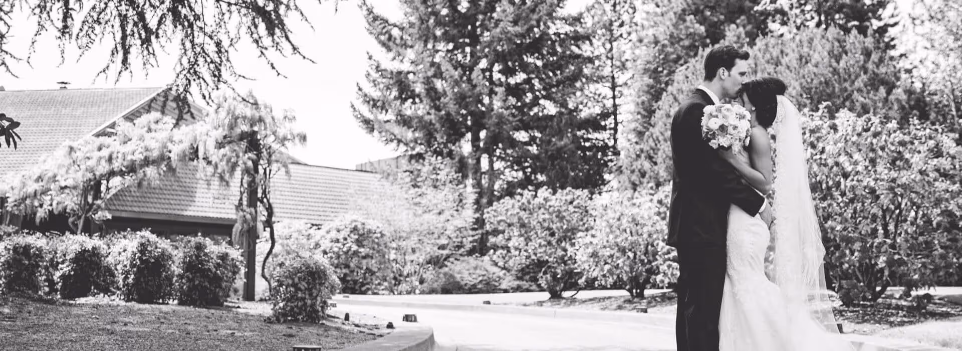 Groom kisses the forehead of his bride in front of the clubhouse