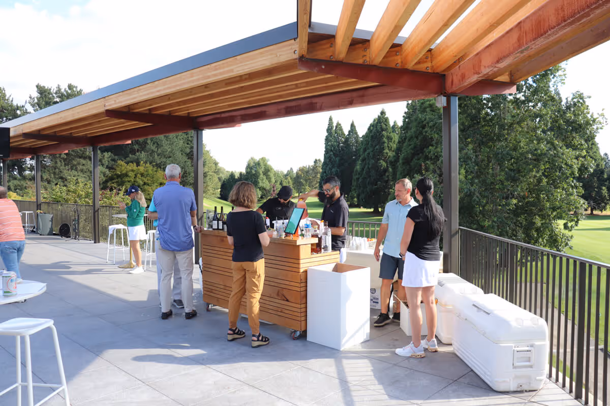 Guests gather around the terrace bar overlooking the lush golf course during an event at Columbia Edgewater