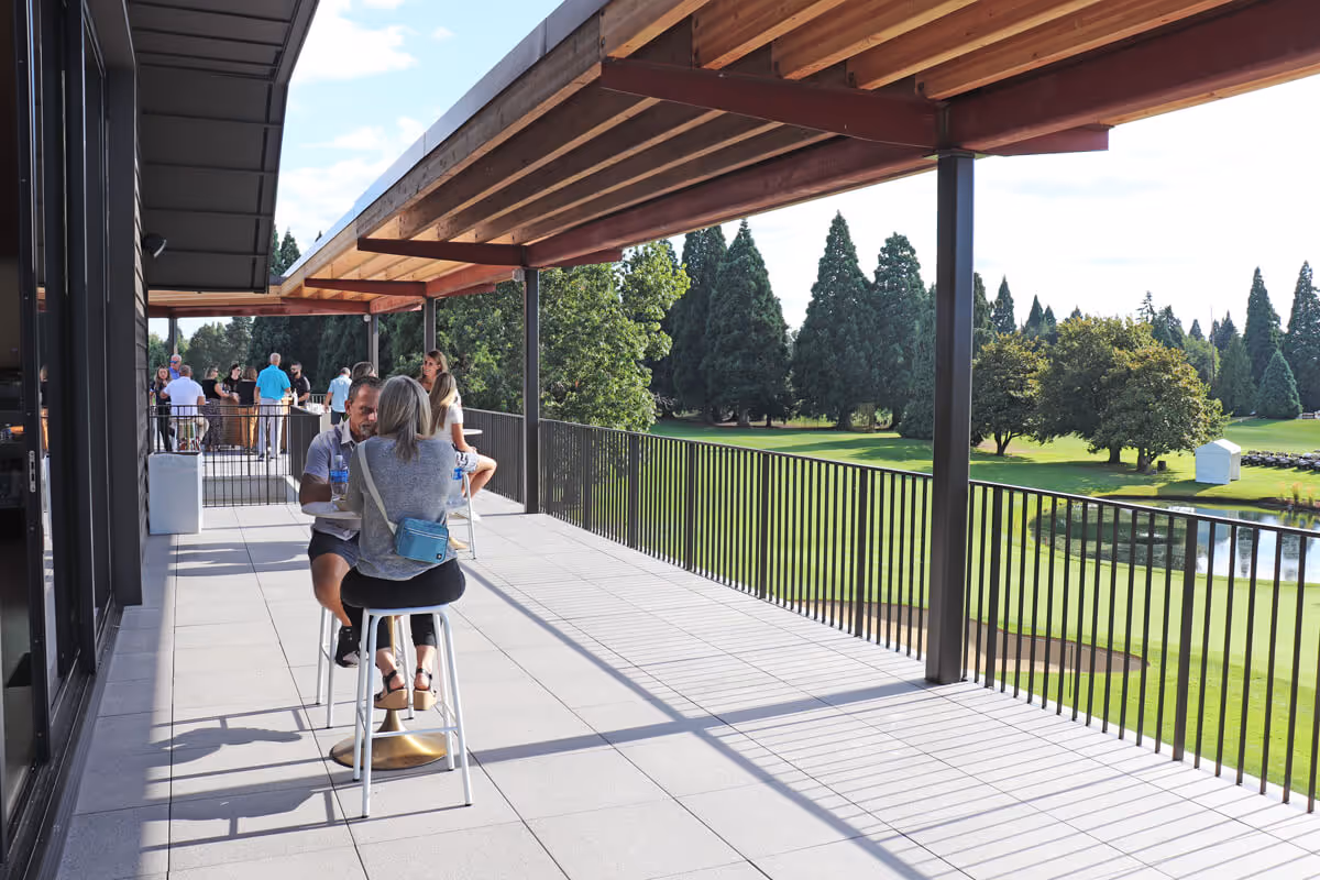 Guests sitting at a table on the terrace overlooking the lush golf course at Columbia Edgewater