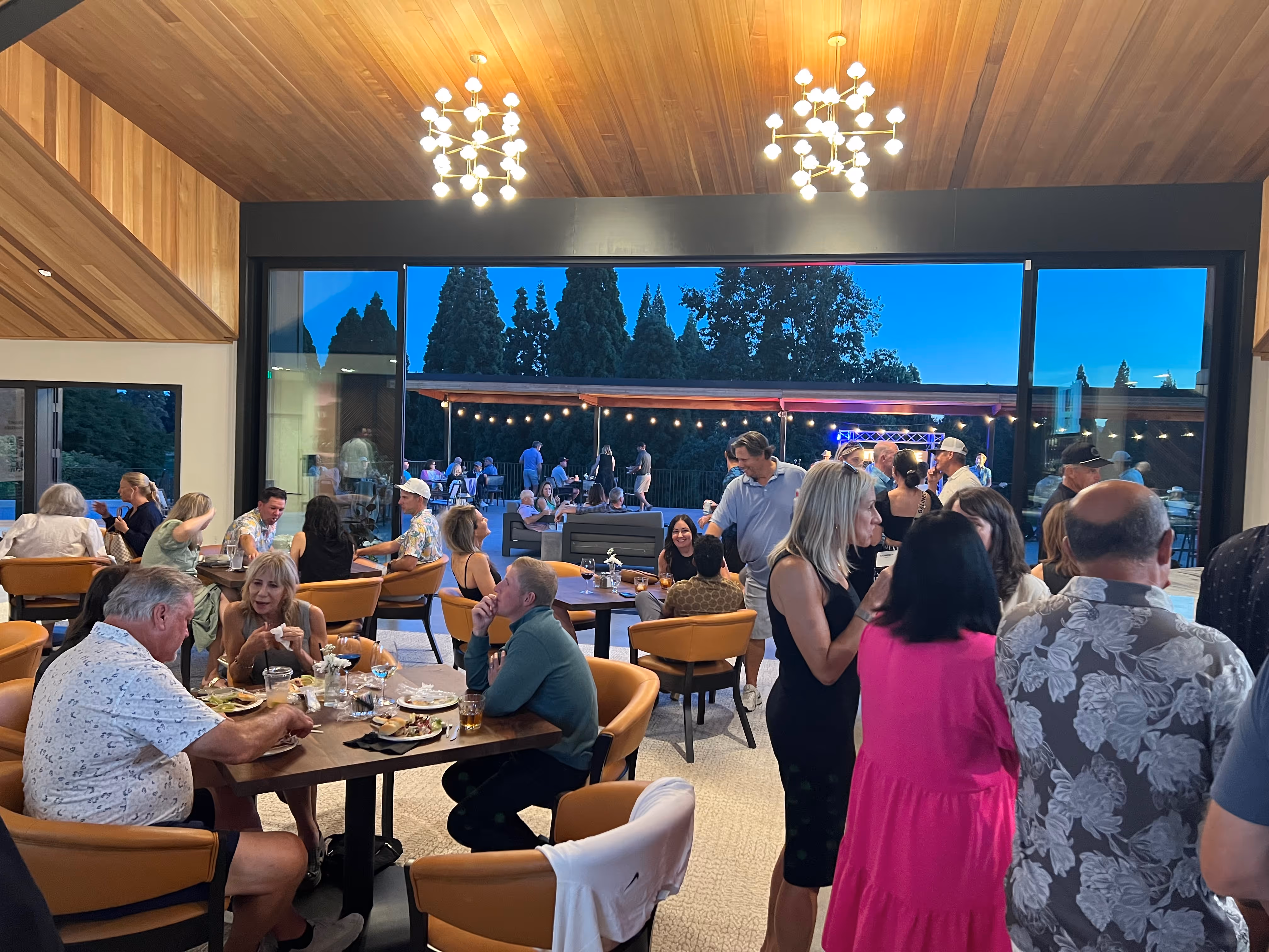 Room filled with people dressed formal having drinks and mingling.