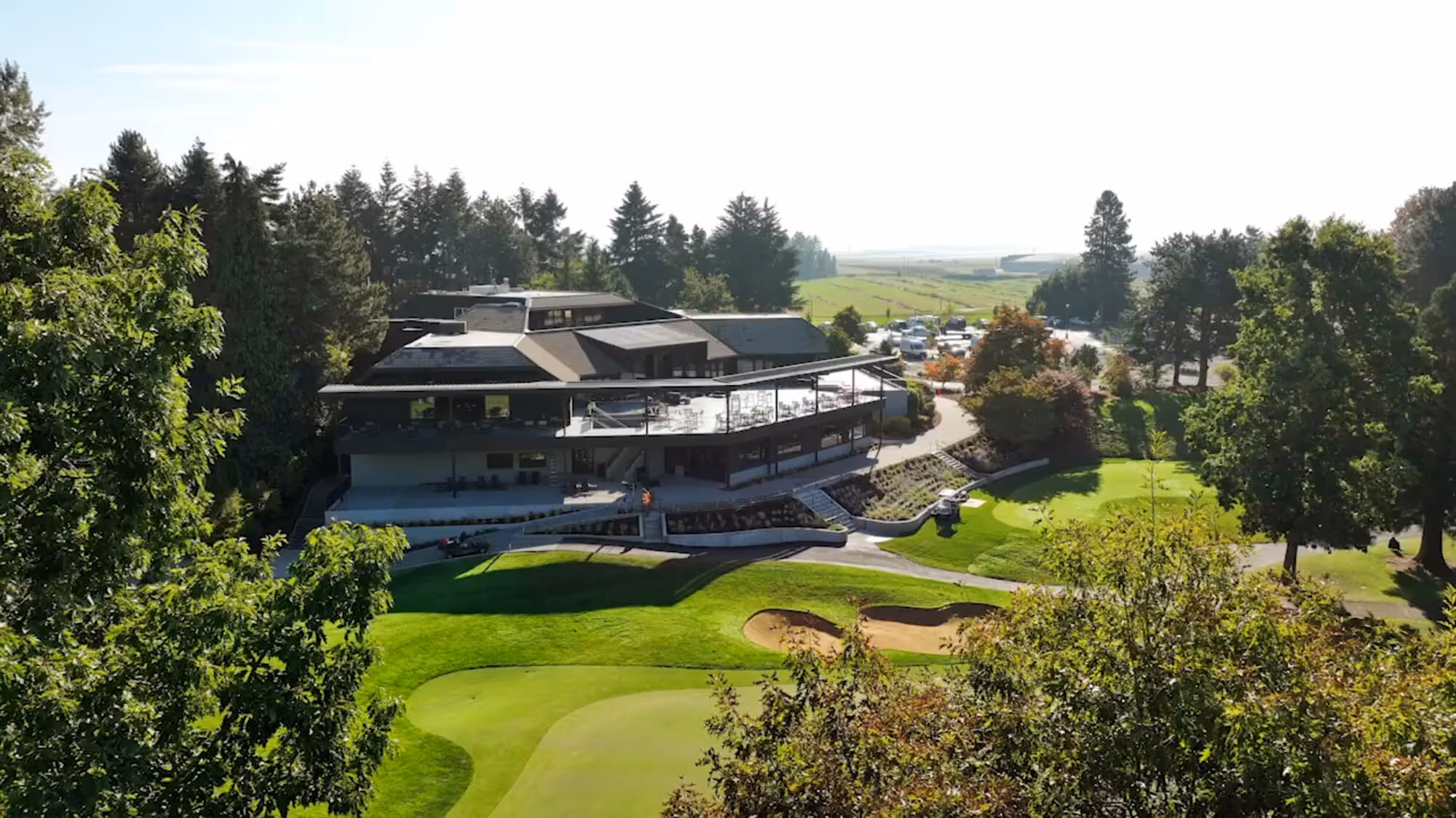 Aerial view of a Columbia Edgewater clubhouse overlooking their lush green golf course with sand traps and surrounding trees.