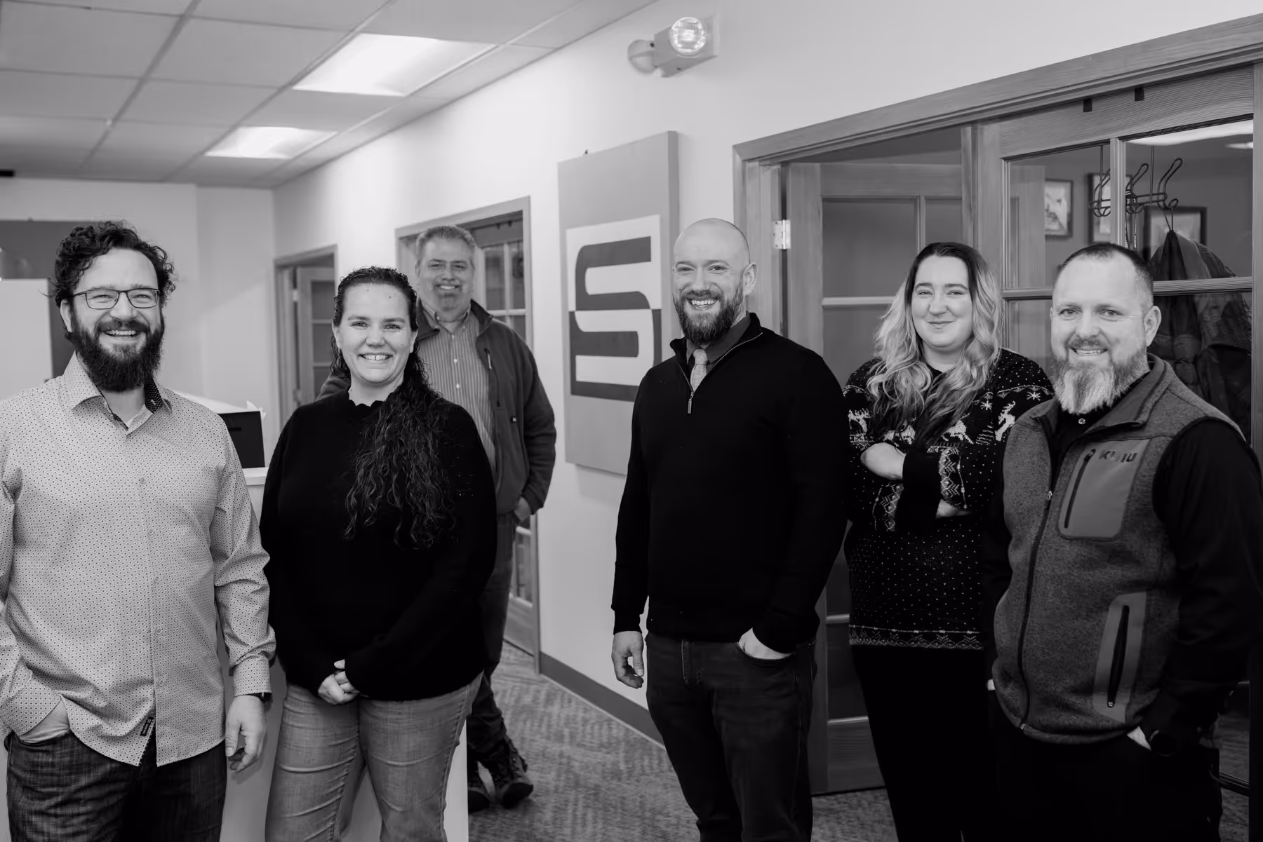 Group photo of the Stratus Services team in the Stratus offices with the logo in the background.