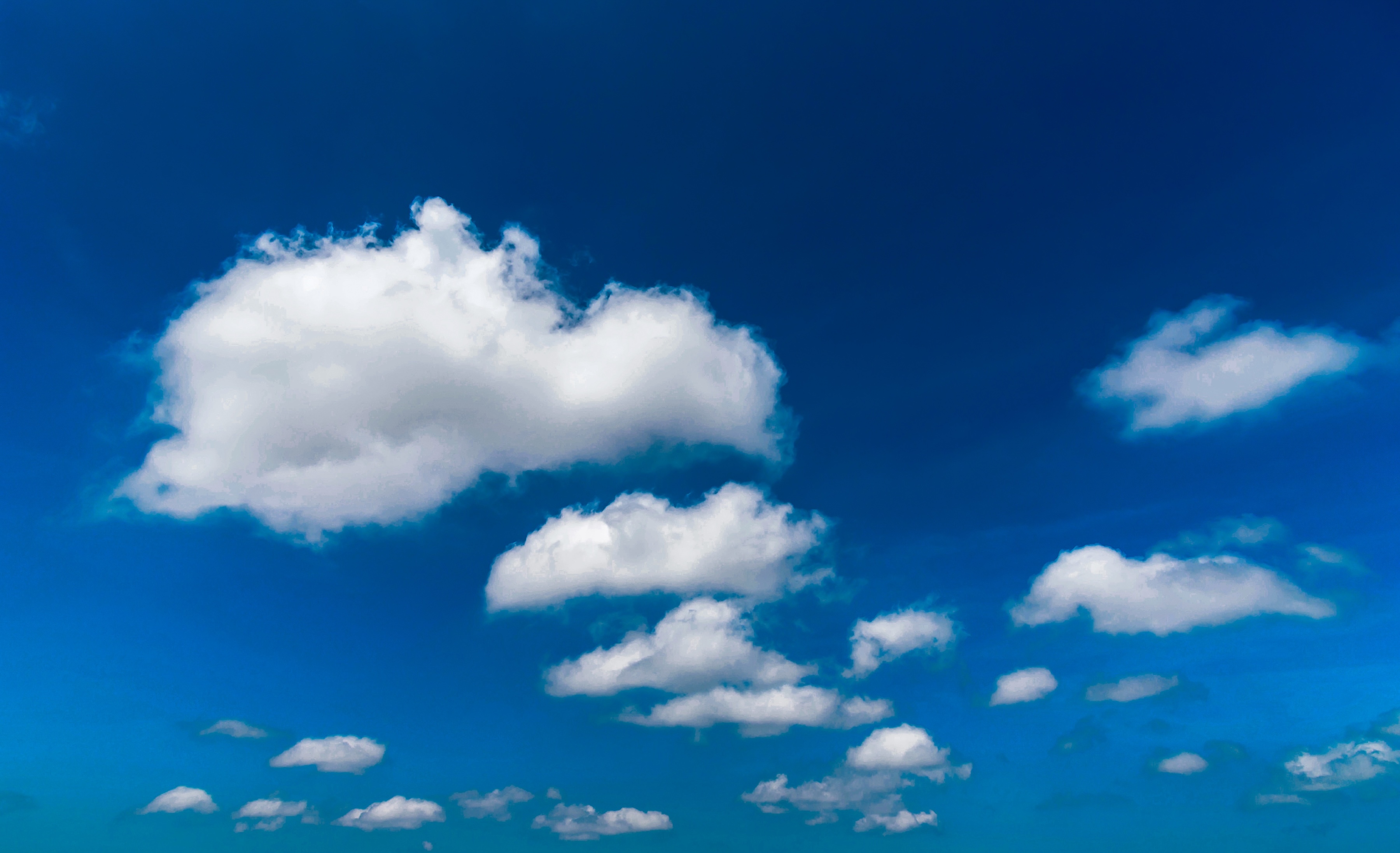 Background image of a blue sky with white, puffy clouds. 