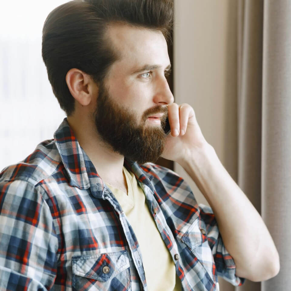 Man in plaid shirt talking on the phone.
