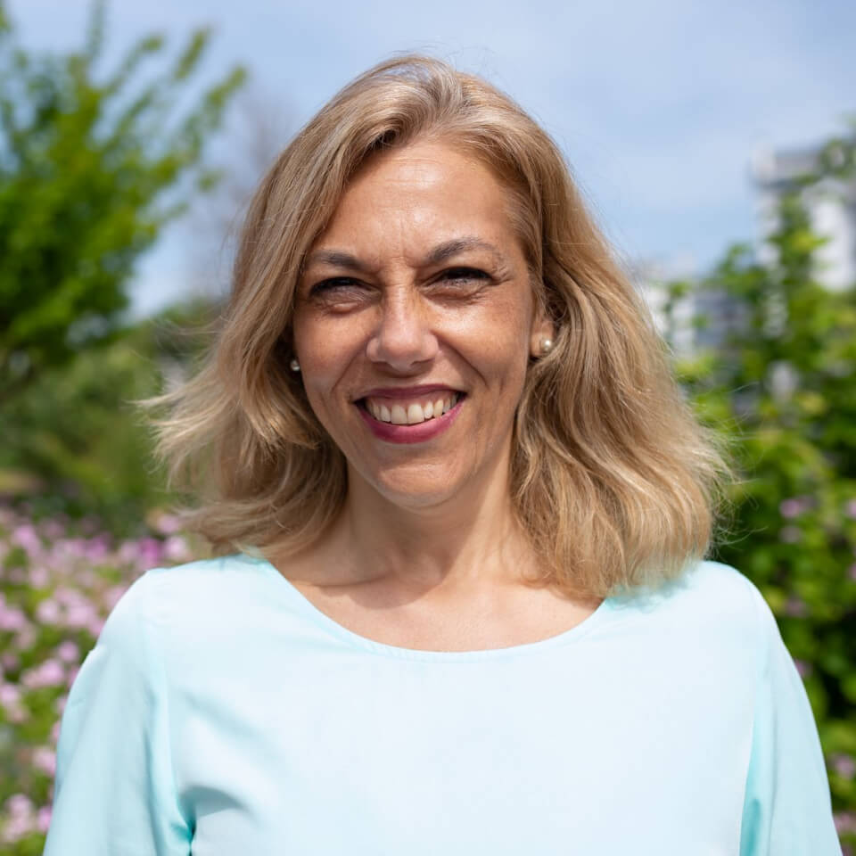 Woman smiling outside with a blue sky behind her.