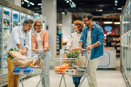 Uma mão segurando um celular que está tirando foto de um Supermercado.