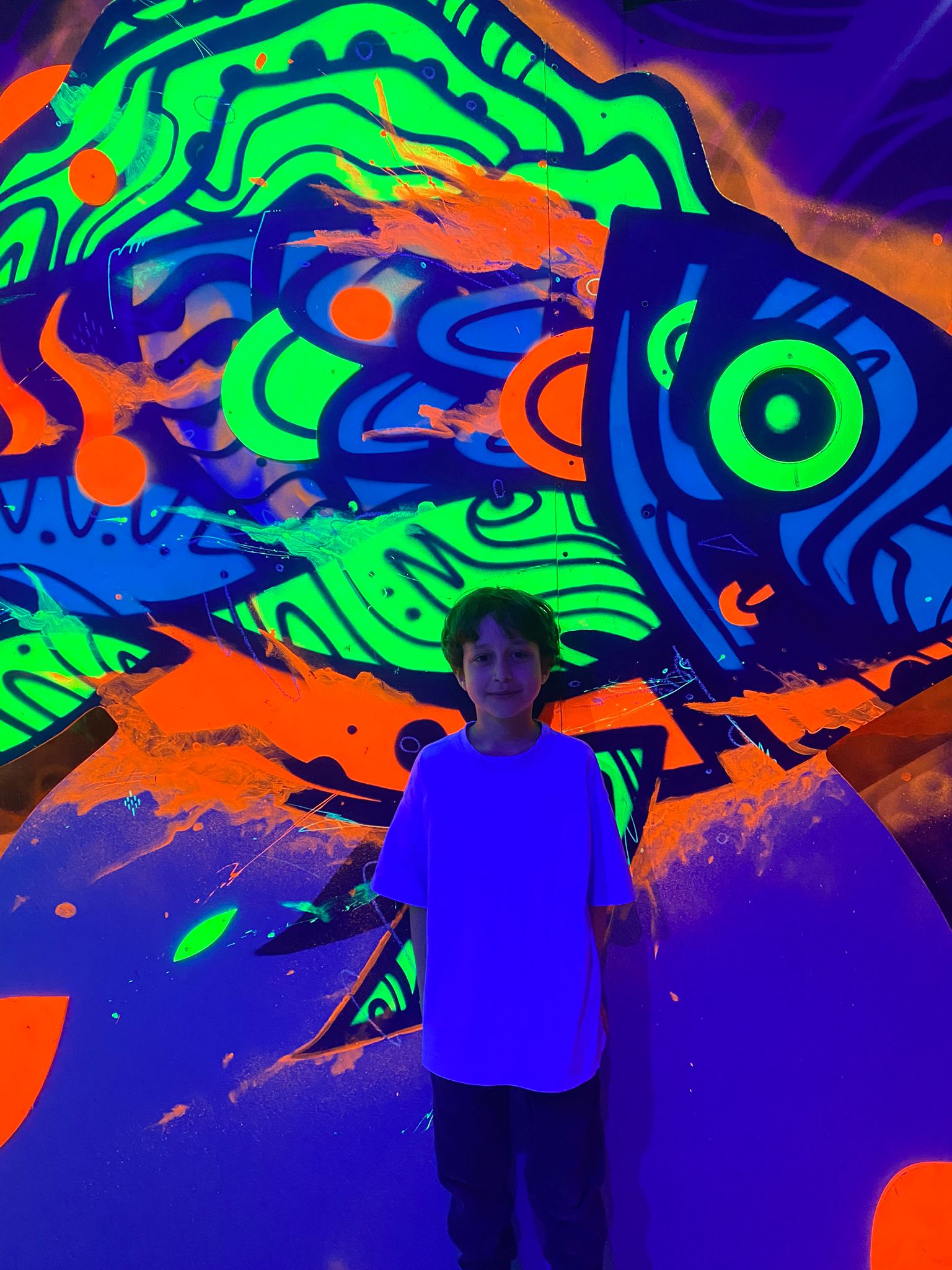 Enfant qui pose devant une fresque néon
