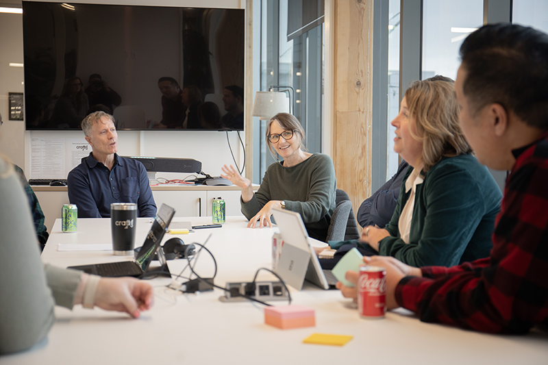 Four coworkers smiling and talking around a meeting table