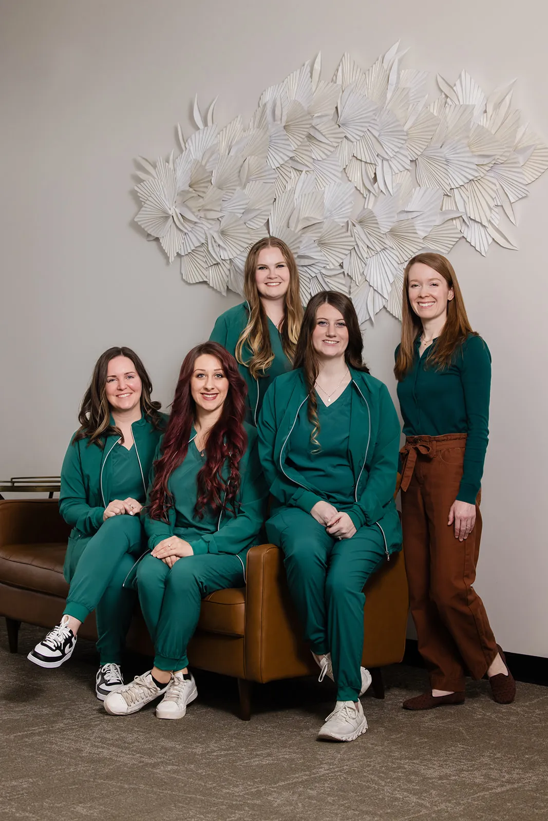 Dr. Maureen Wood and the Rochester Family Orthodontics team, five smiling women with four seated in green scrubs.