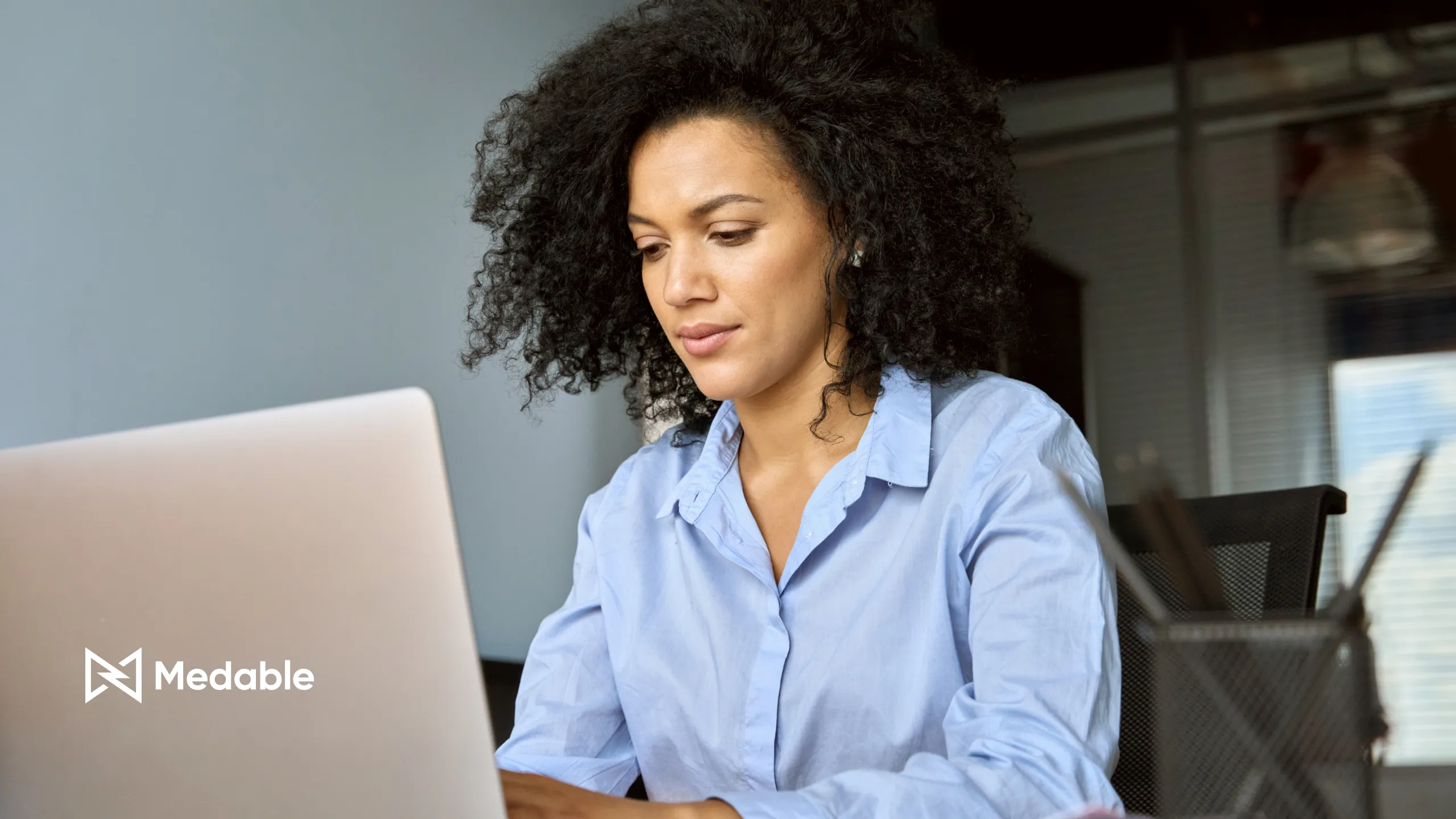 businesswoman sitting at desk working typing on laptop computer in contemporary corporation office. Business technologies concept.