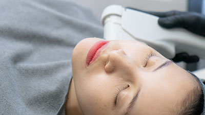Une femme en train de se faire traiter le visage avec des ultrasons focalisés de haute intensité (HIFU).