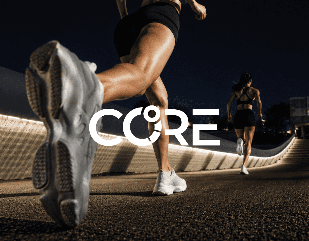 Two women running outdoors at night on a lit pathway wearing black sportswear and white shoes.