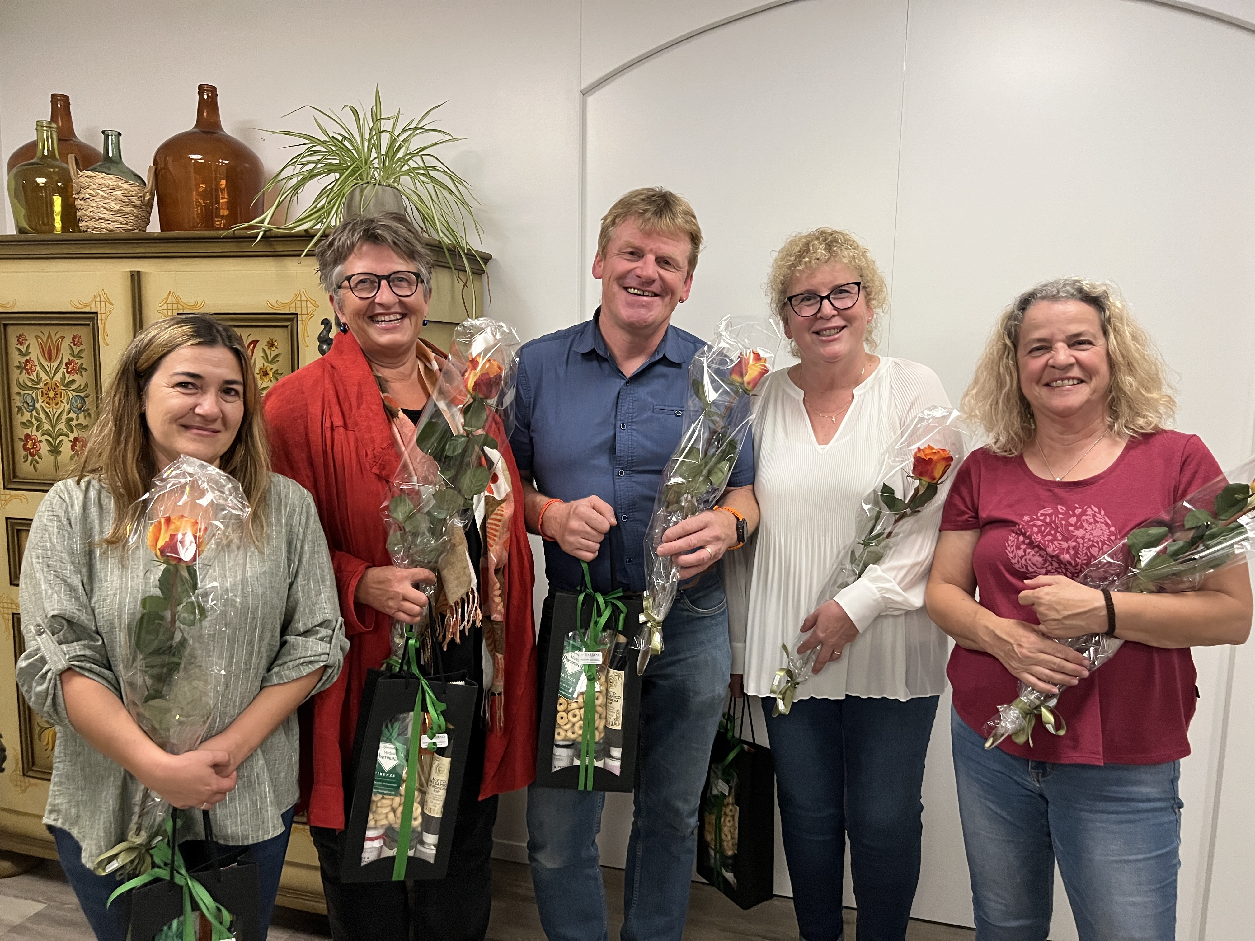 Fünf Mitarbeitende mit Rosen und Geschenktaschen bei der Ehrung