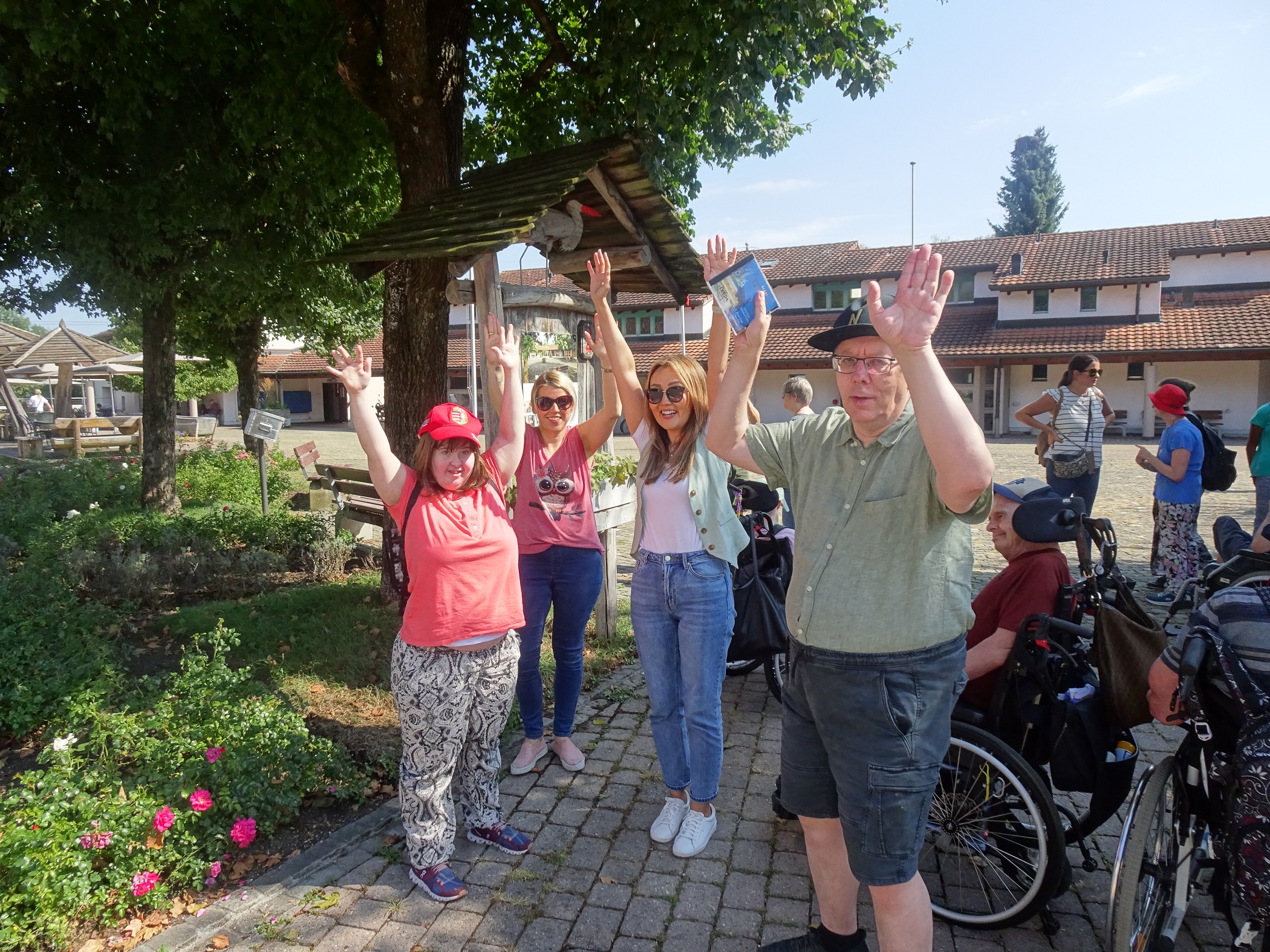 Gruppe winkt fröhlich auf einem Dorfplatz bei einem Ausflug