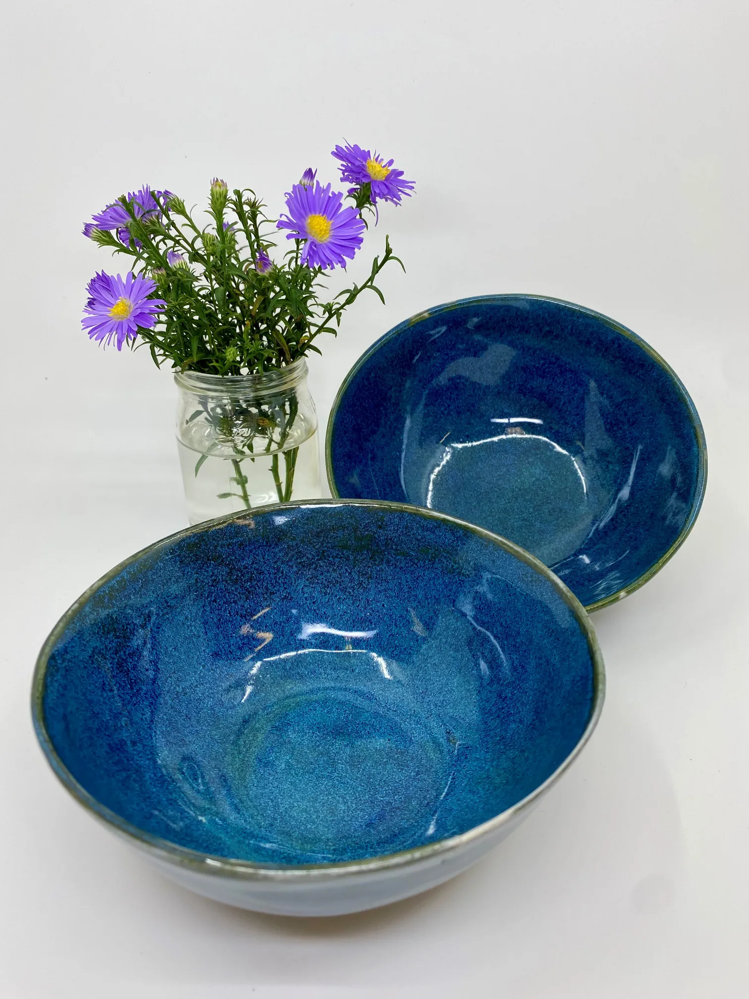 Zwei blau glasierte Keramikschalen aus dem Atelier, daneben ein Blumenstrauss