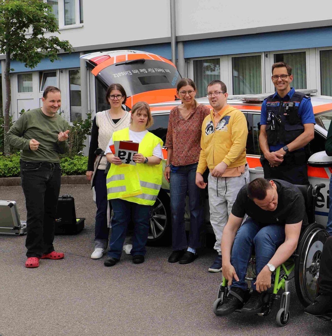 Gruppe mit einem Polizisten vor einem Polizeiauto