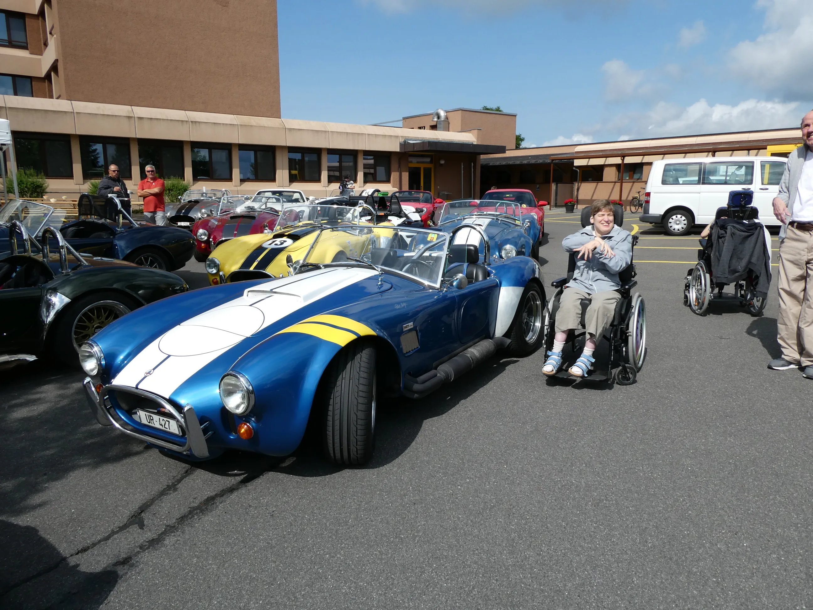 Oldtimer-Sportwagen auf einem Parkplatz, Gäste schauen zu