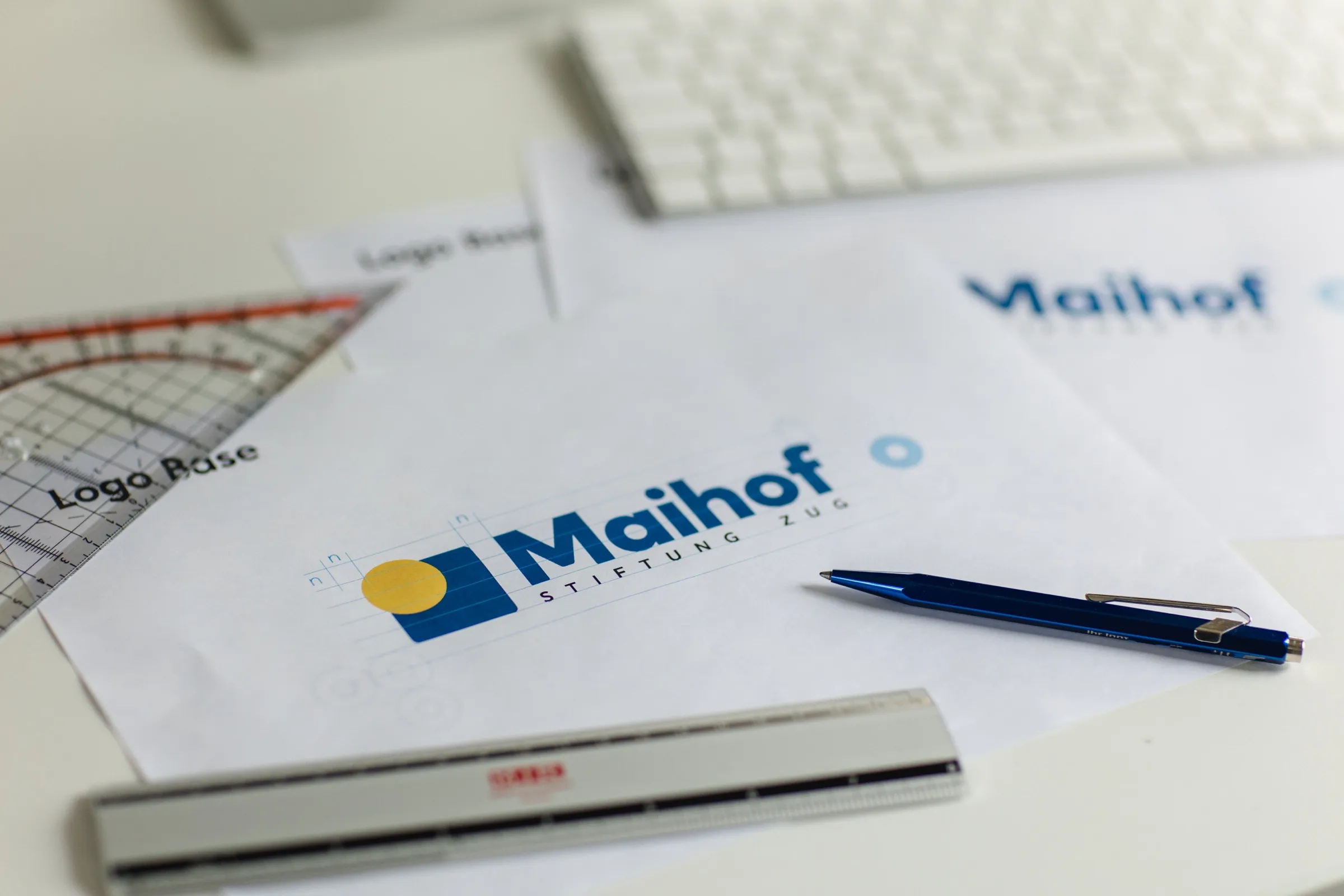 Logo der Stiftung Maihof auf Gestaltungsskizzen mit Lineal und Kugelschreiber