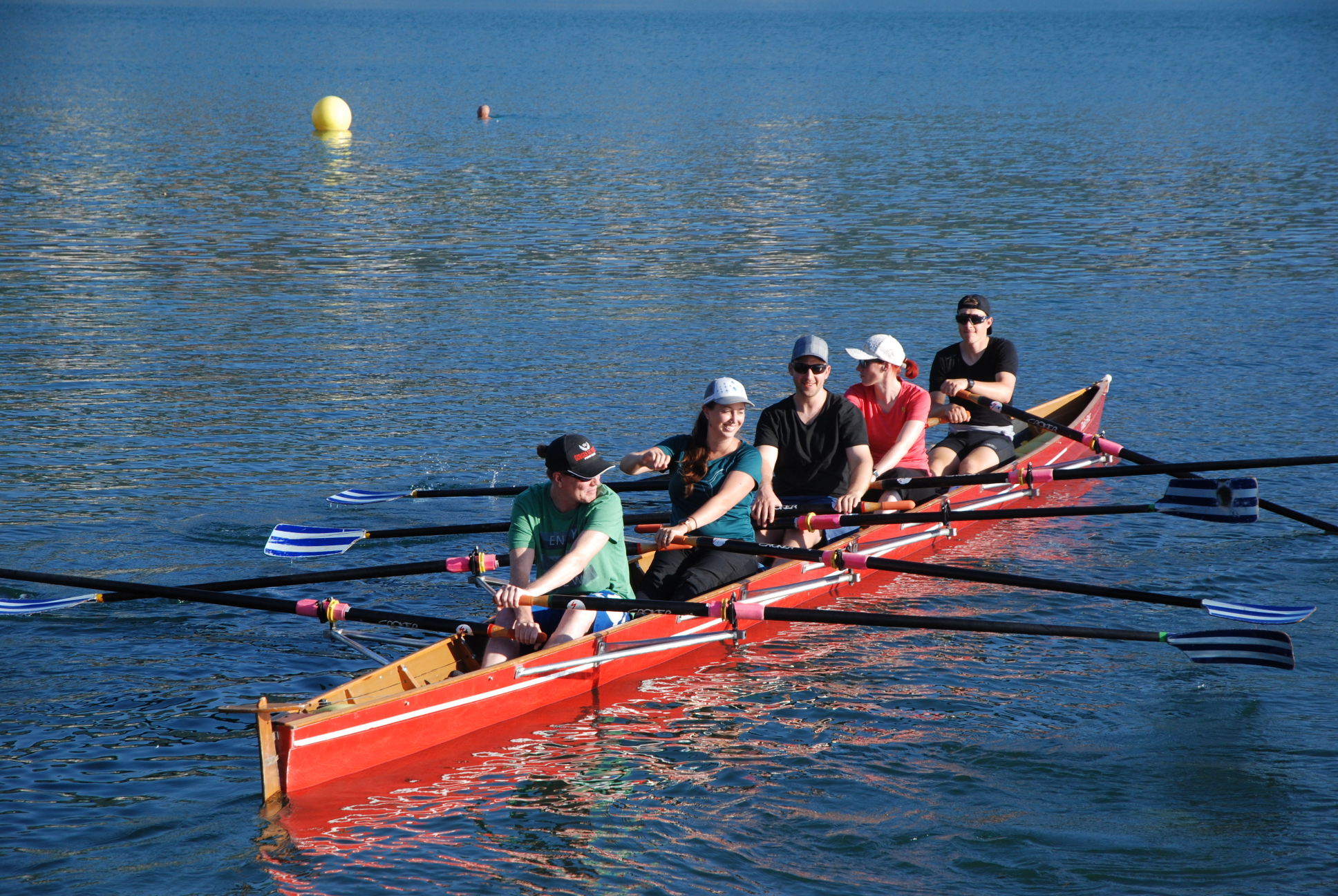 Leitungsteam rudert in einem roten Ruderboot auf dem Zugersee