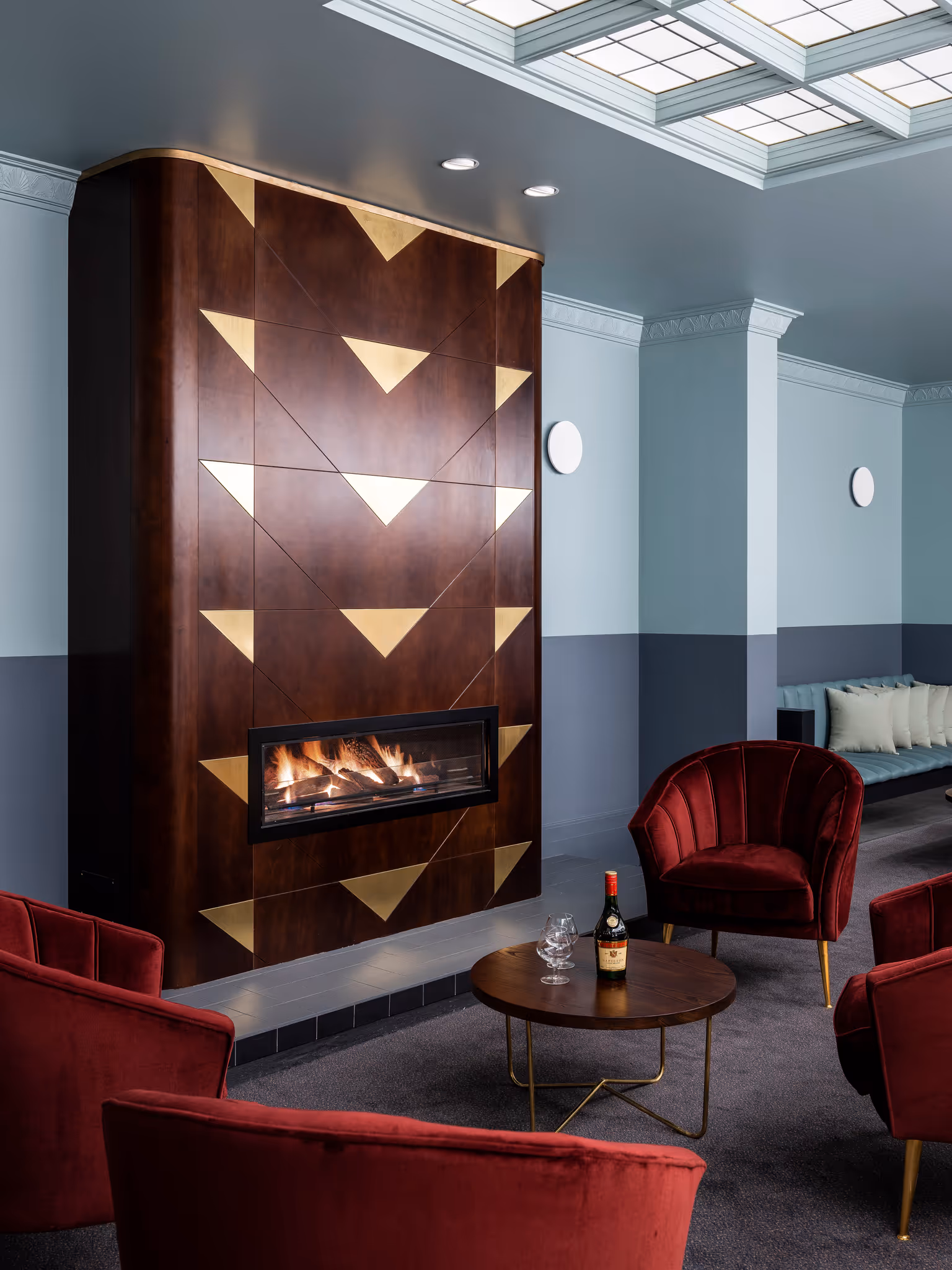 single red couches around small timber coffee table in front of fireplace in bar at tattersalls hotel Armidale 