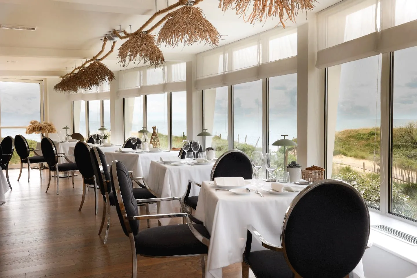 La Table du Grand Large's elegant dining room with large windows offering a spectacular view of the ocean sunset