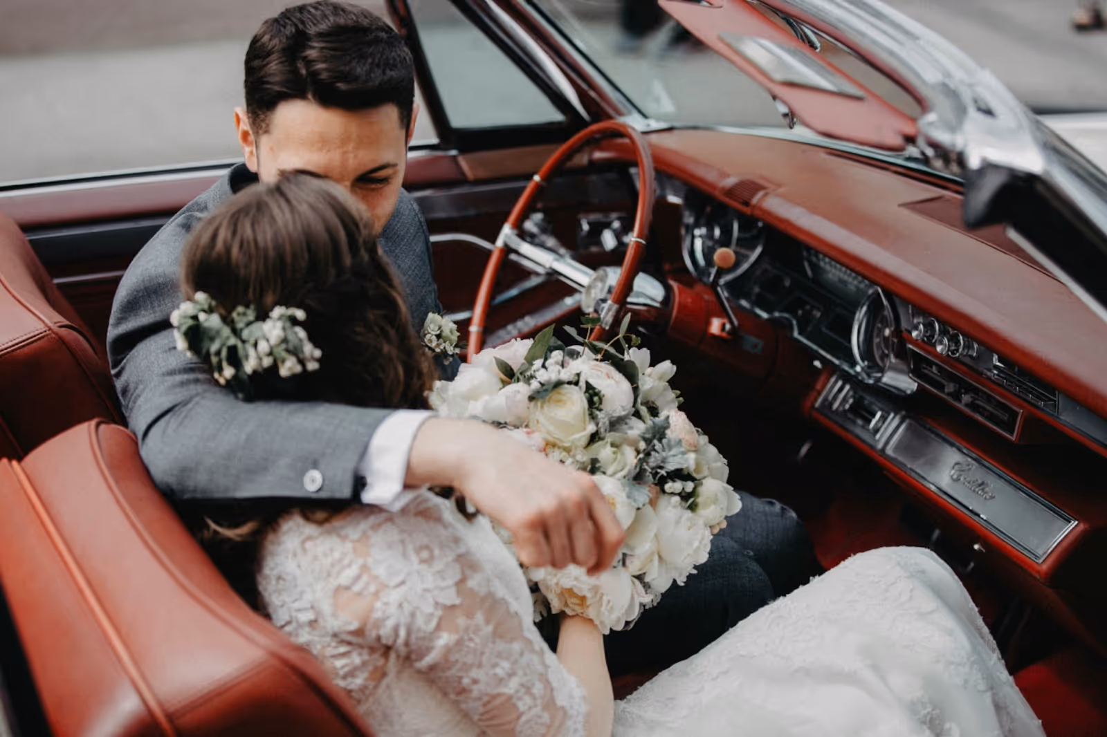 deux mariés amoureux dans une voiture vintage