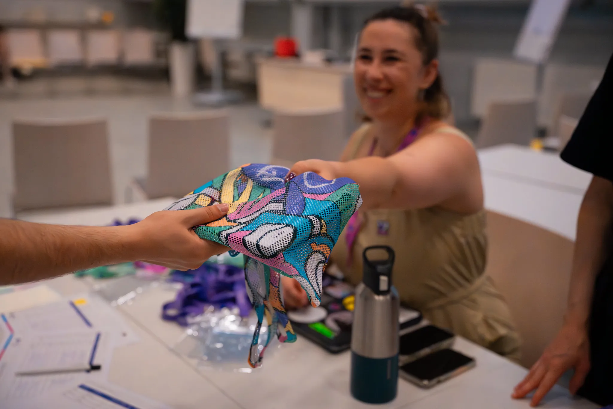 Picture of a hand handing a laniard with the previous IGLYO logo on it at the Annual Members' Conference Brussels 2022.