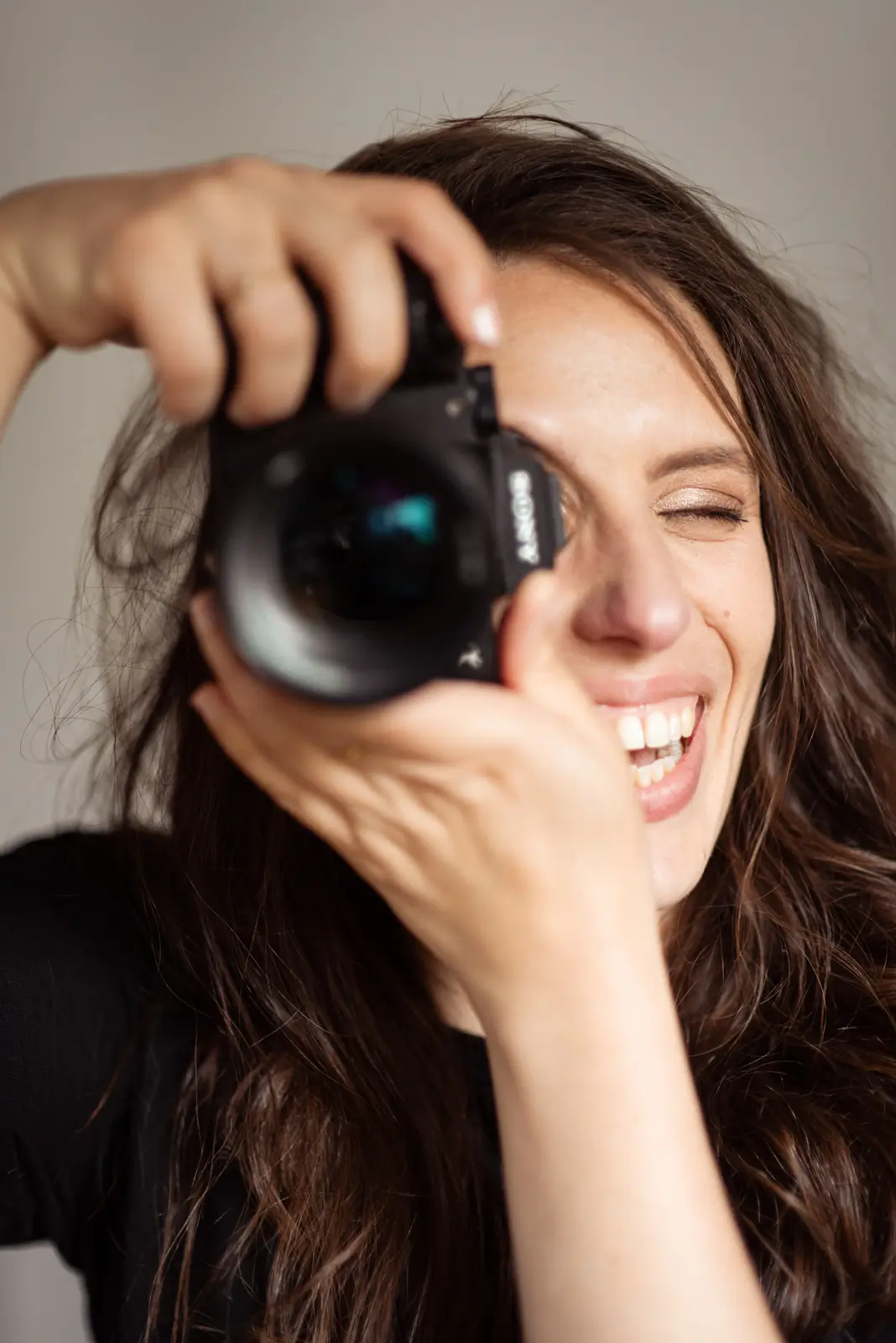 Delphine Saliou - Photographe. Femme souriante derrière son appareil photo.