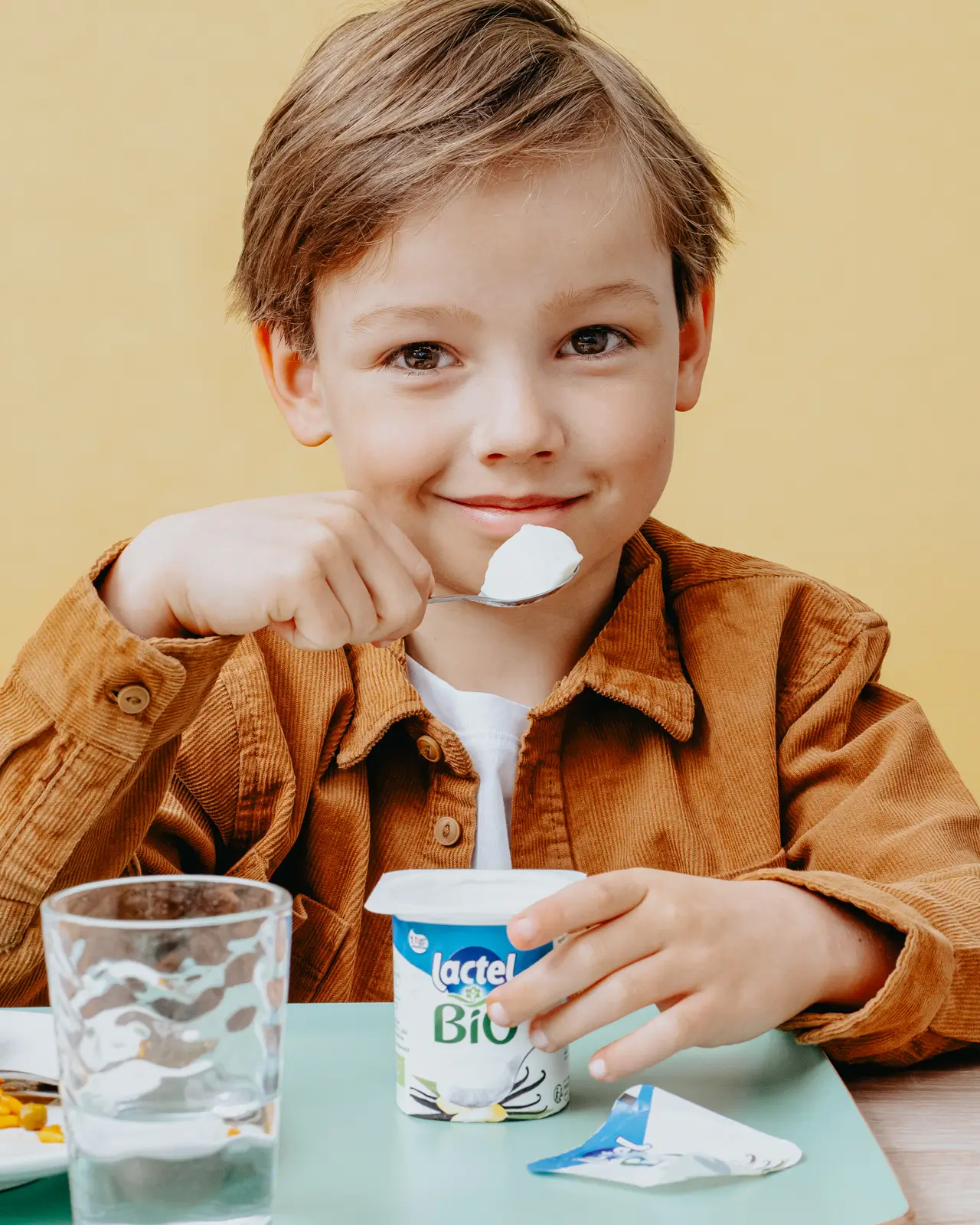 Publicité pour Lactel Bio, garçon dégustant un yaourt à la vanille. Ambiance culinaire avec mannequin enfant.