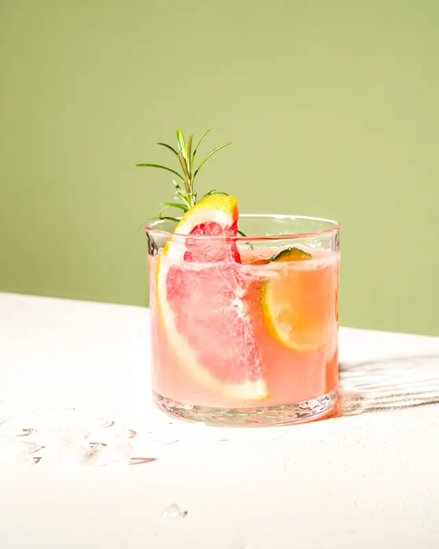 Photo boisson minimaliste studio, éclairage solaire. Mocktail Pamplemousse et romarin.