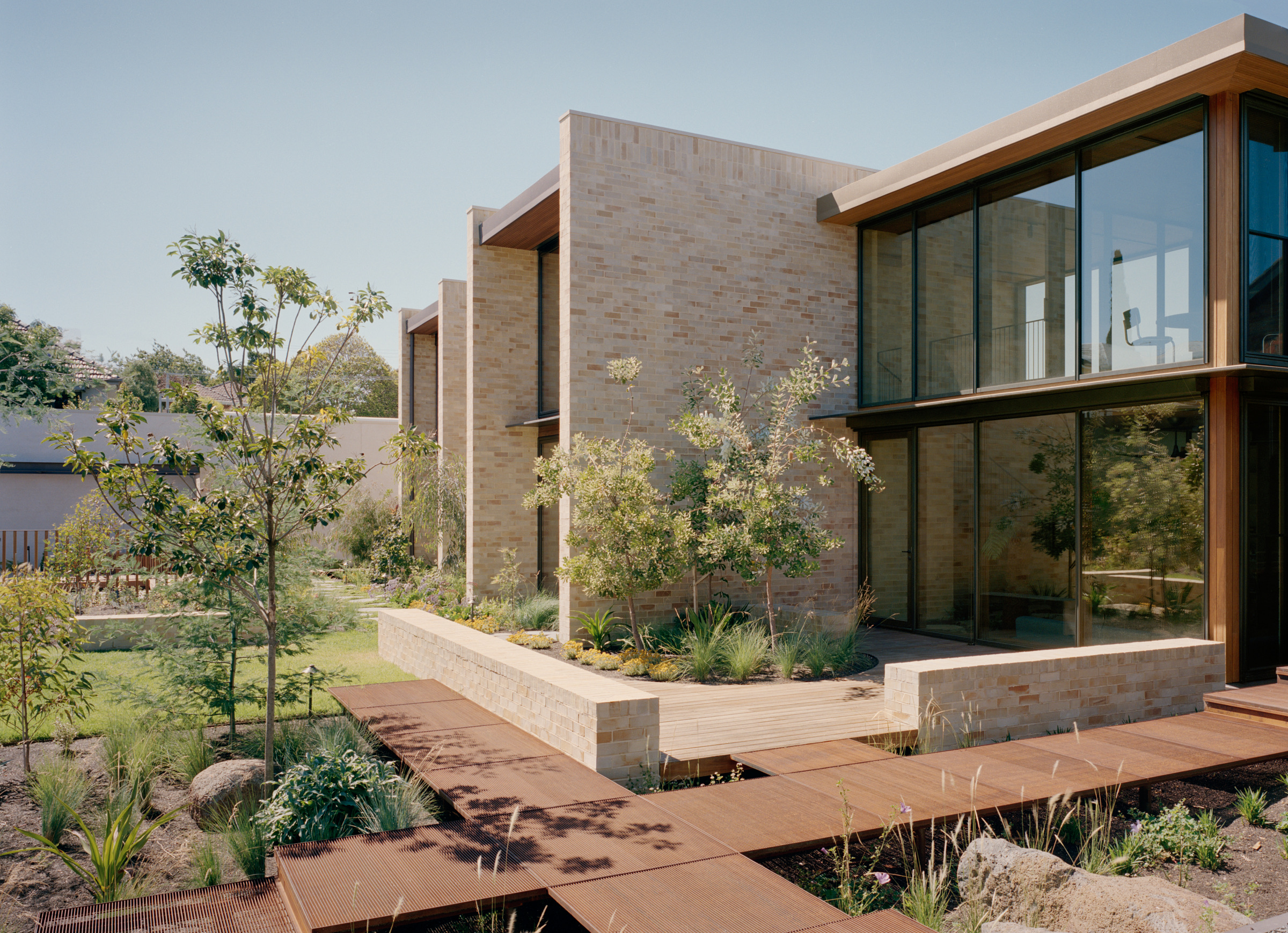 Timber-framed façade glazing beside the planted garden and boardwalk.