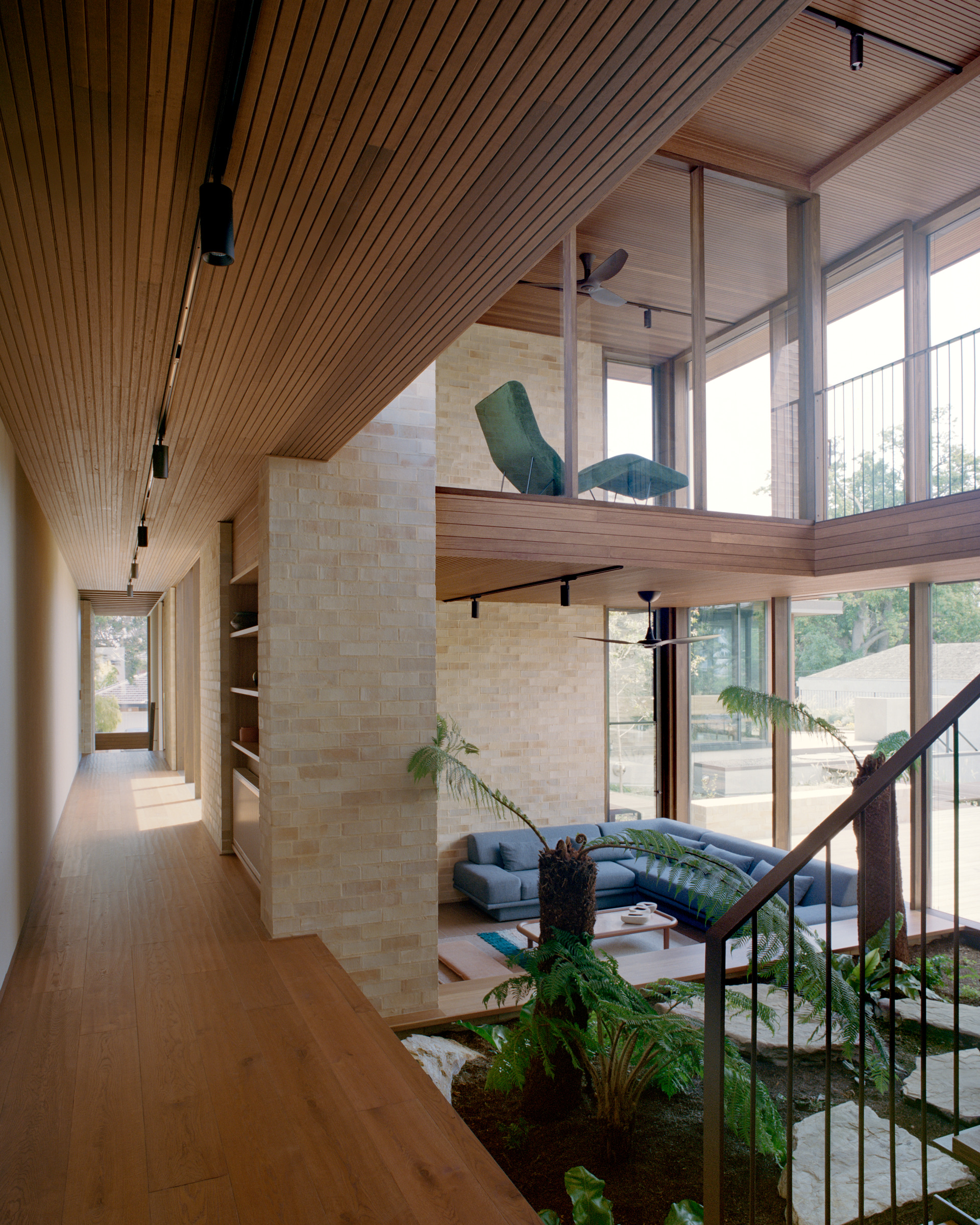 Upper hallway with timber-framed glazing overlooking the living space.