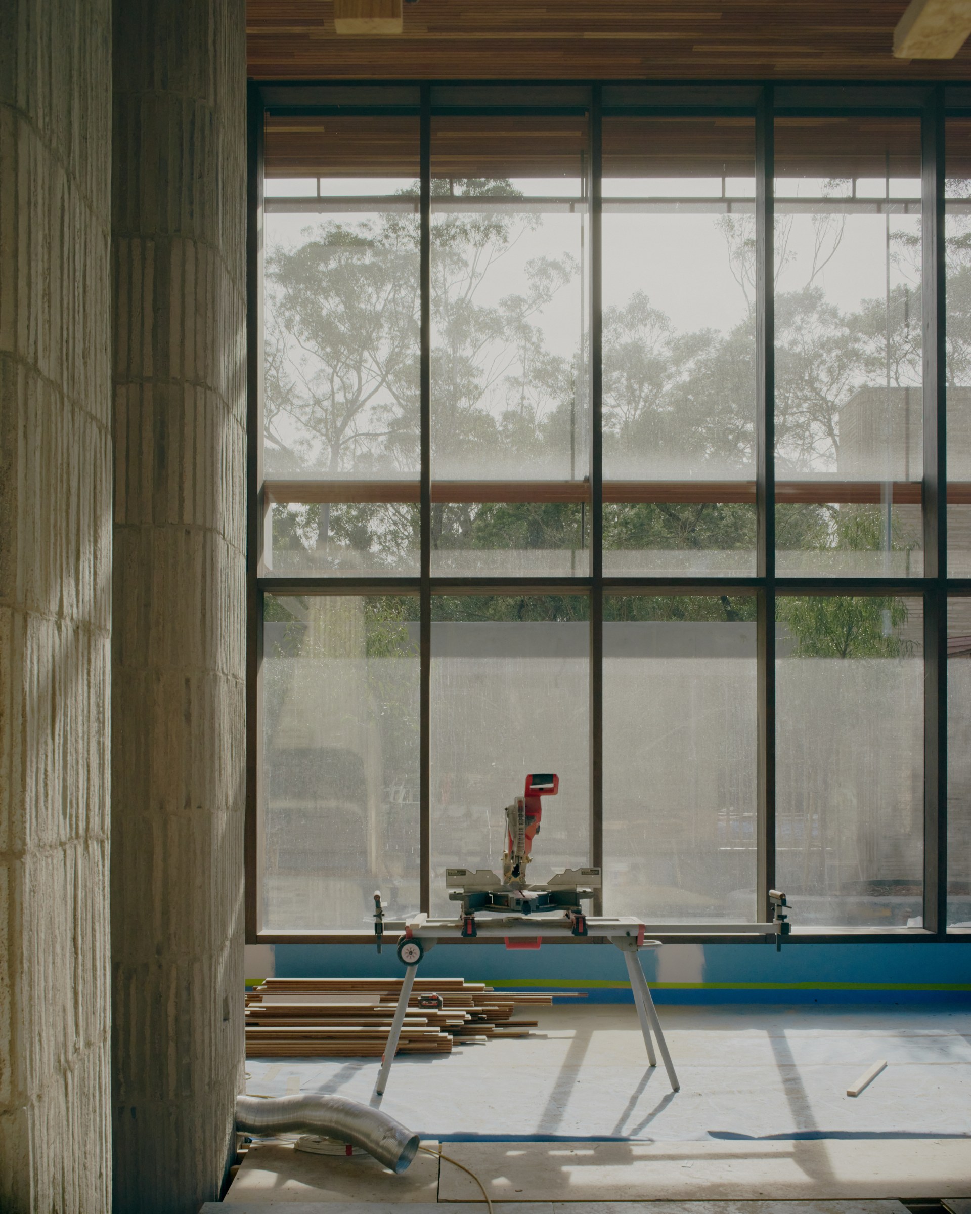 Timber-framed glazing overlooking trees during construction.