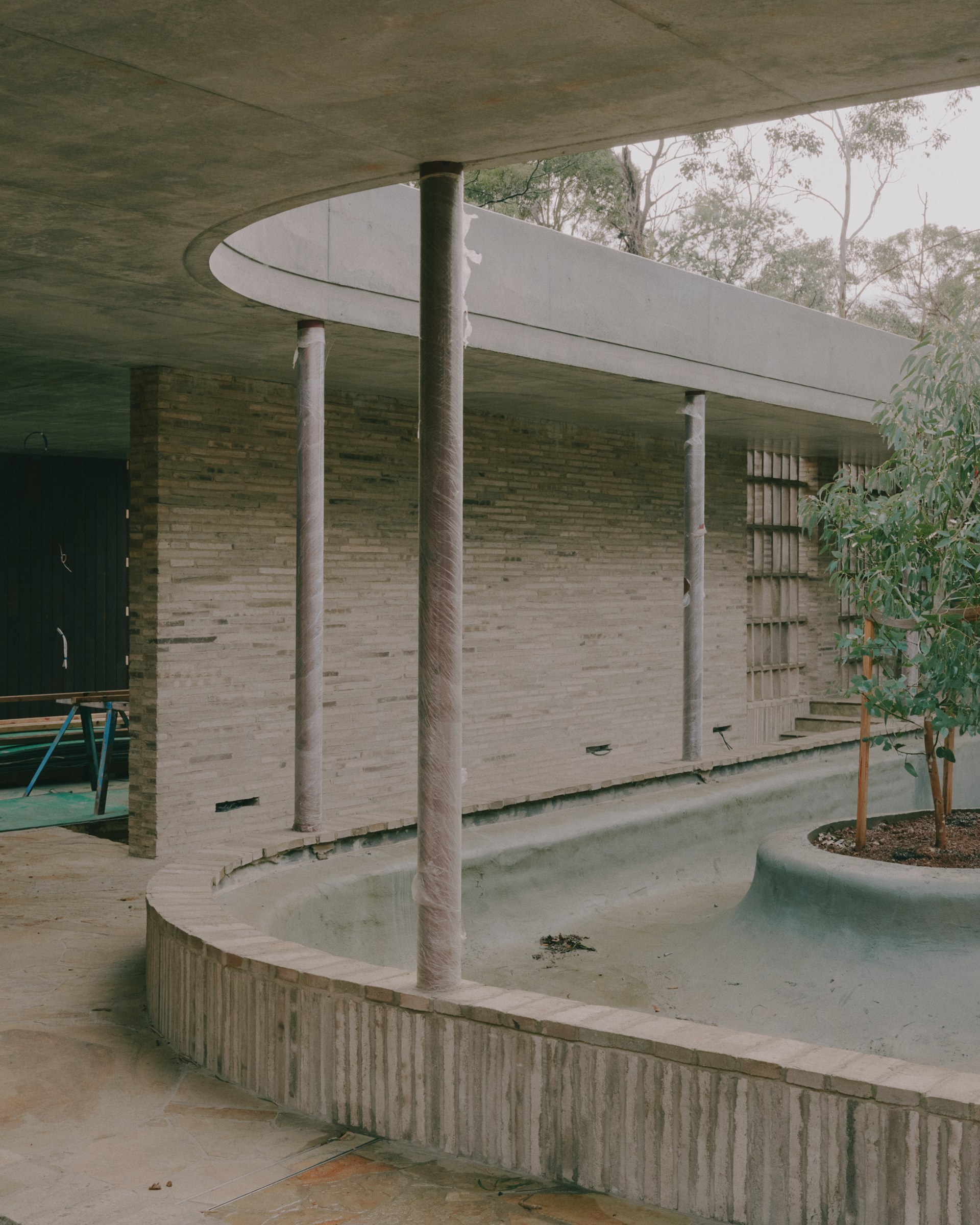 Curved concrete canopy and brick wall at Anchor House during construction.