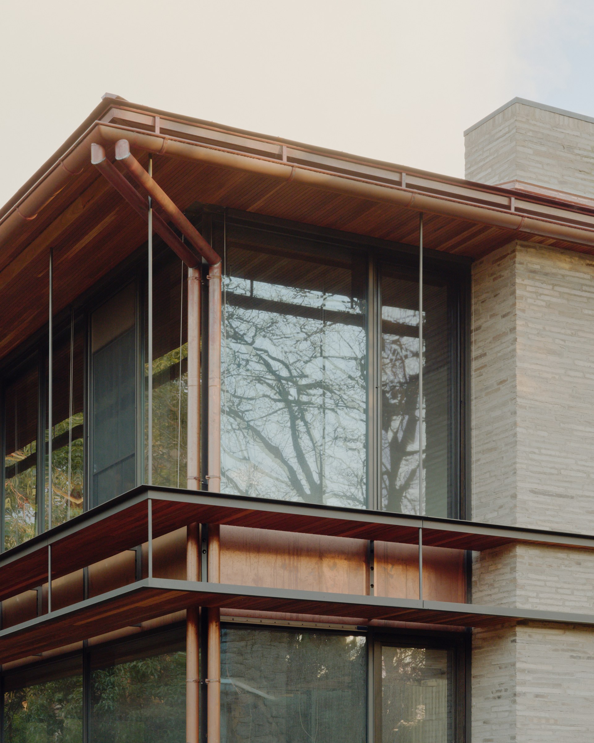 Deep timber façade framing and glazing at a pavilion corner during construction.
