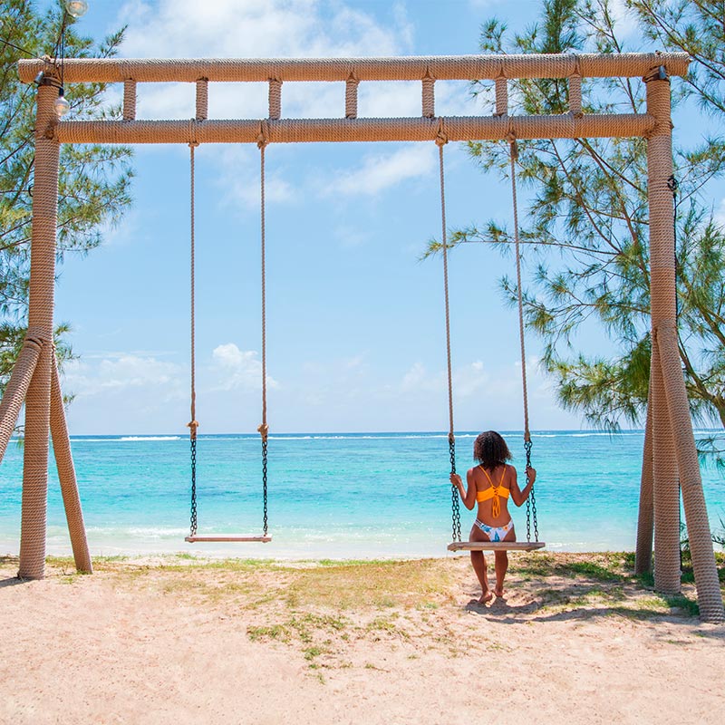 Lady on beach swing looking at the turquoise lagoon