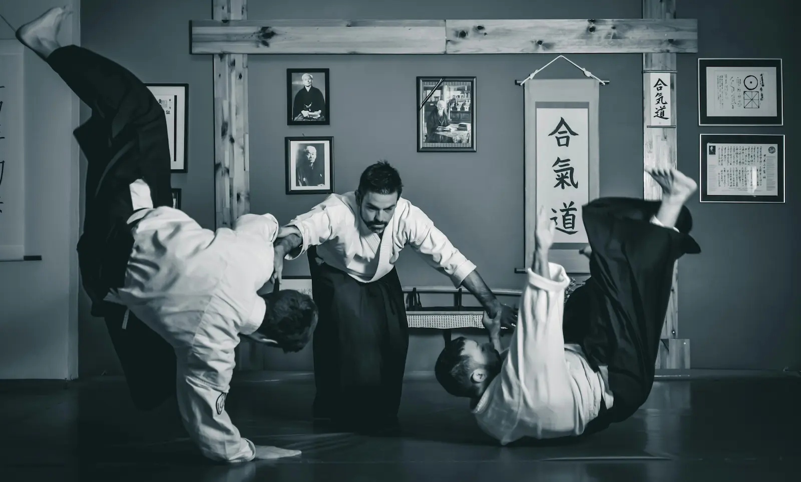 aikido practioner demonstrates technique against two opponents