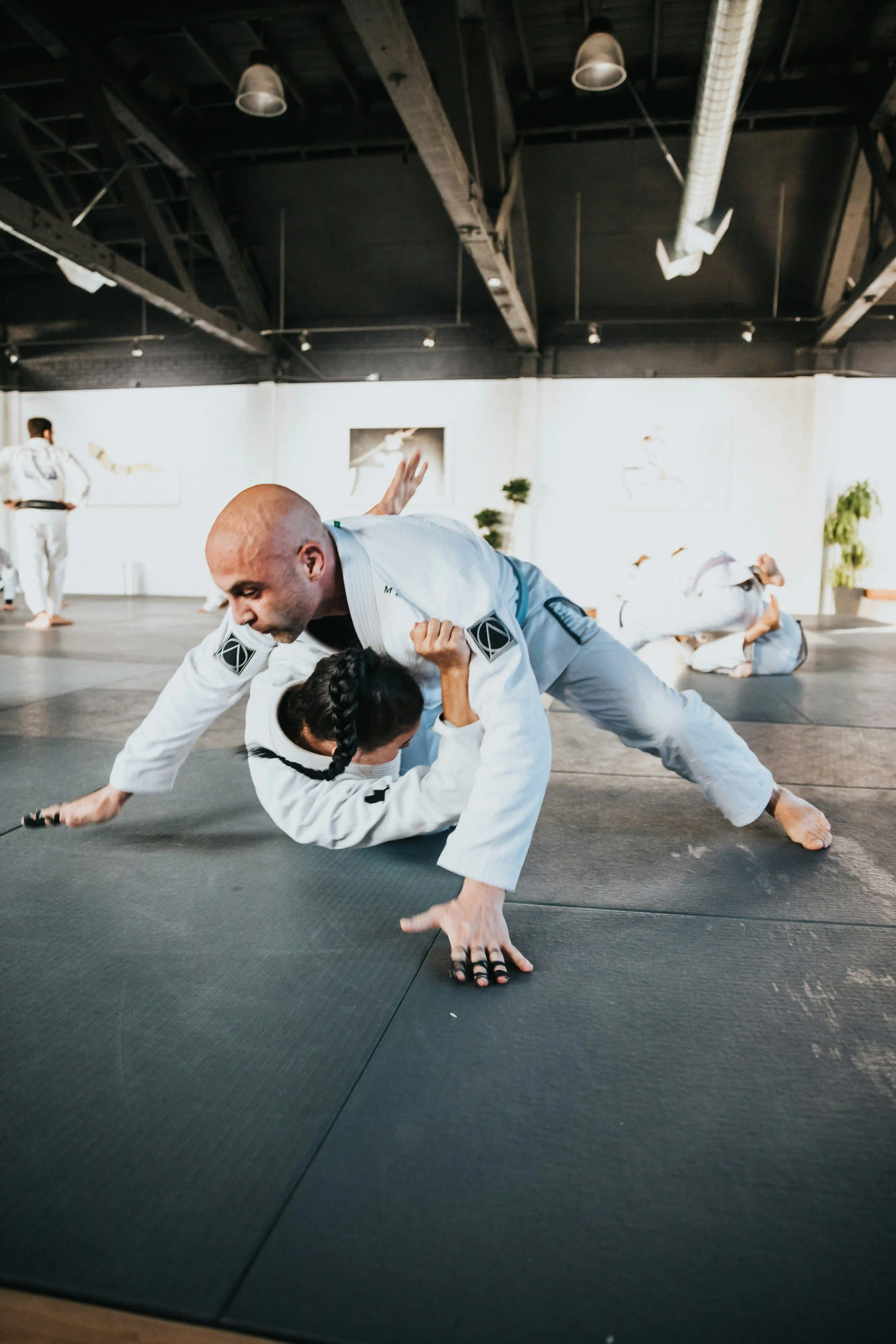 A jiu jitsu white belt practising a hip escape on the mat during a beginner class