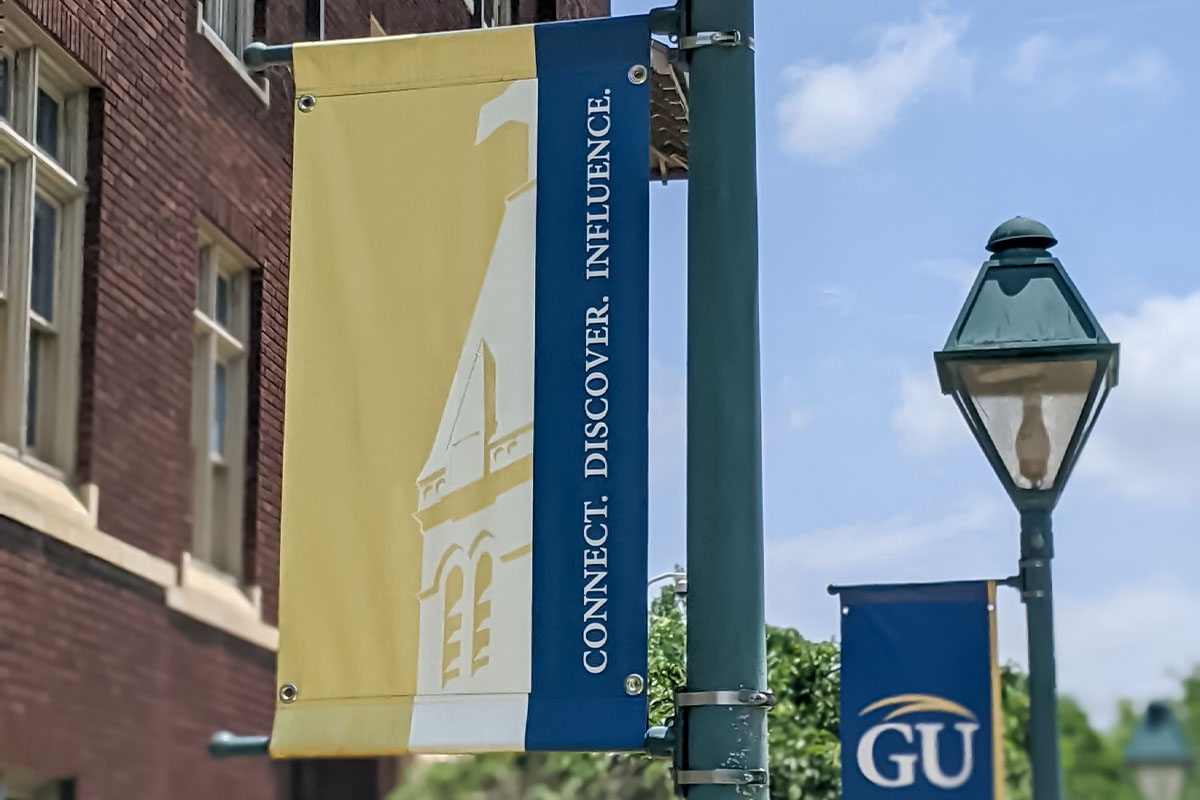 Street banner with a building silhouette and the text: Connect. Discover. Influence.