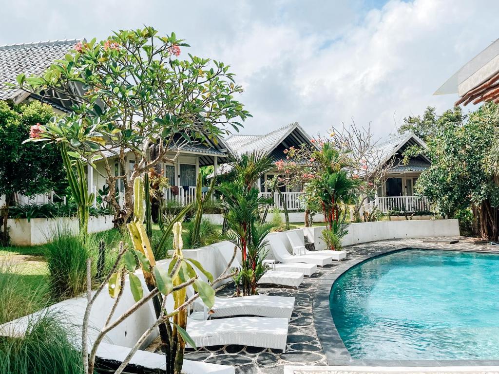 a swimming pool with white lounge chairs next to a house at Bingin Sun & Moon Villas in Uluwatu