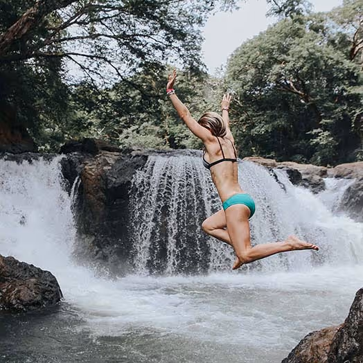 Woman jumping into waterfall on an excursion in Costa Rica