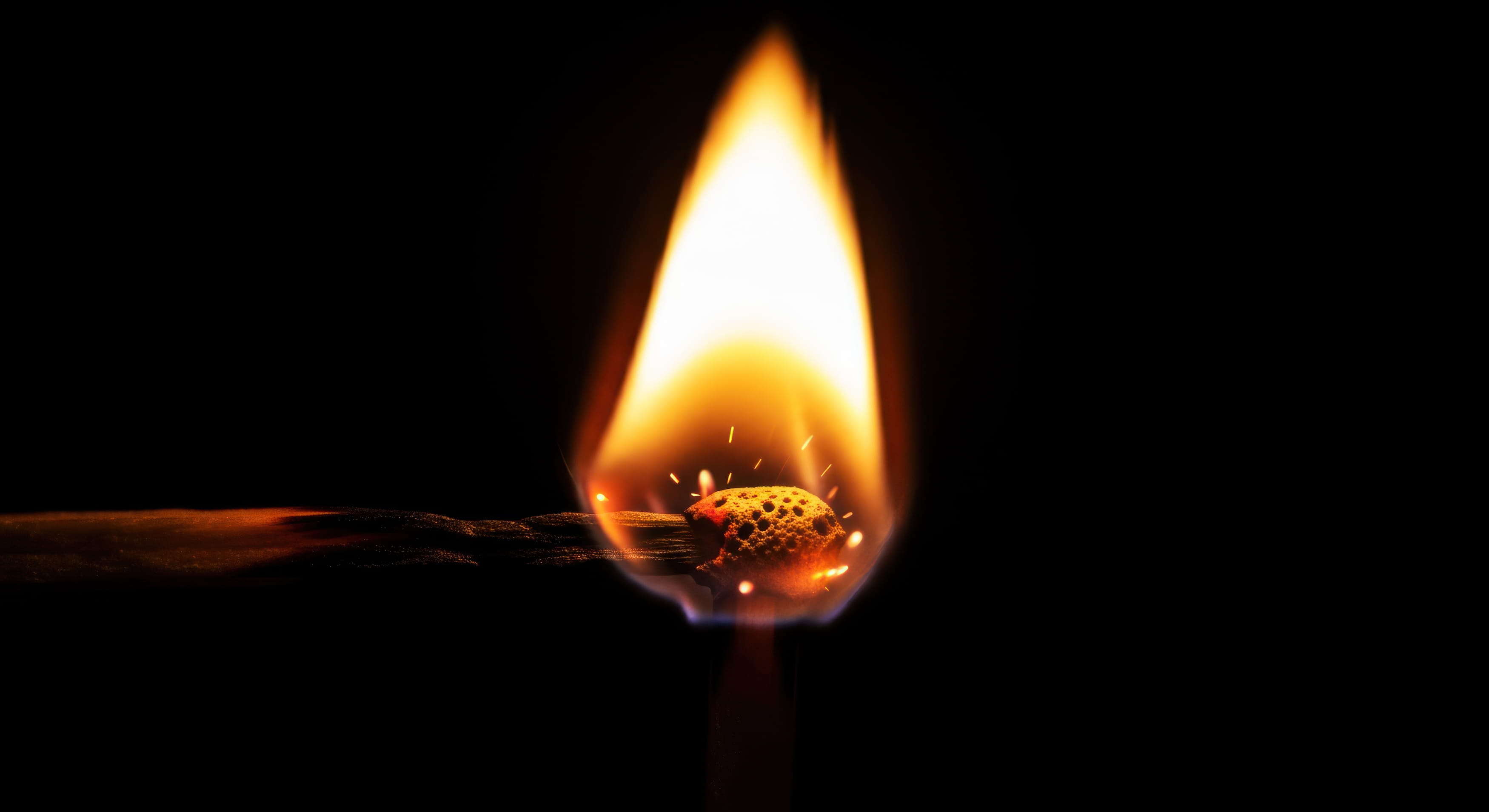 A single match burning against a black background