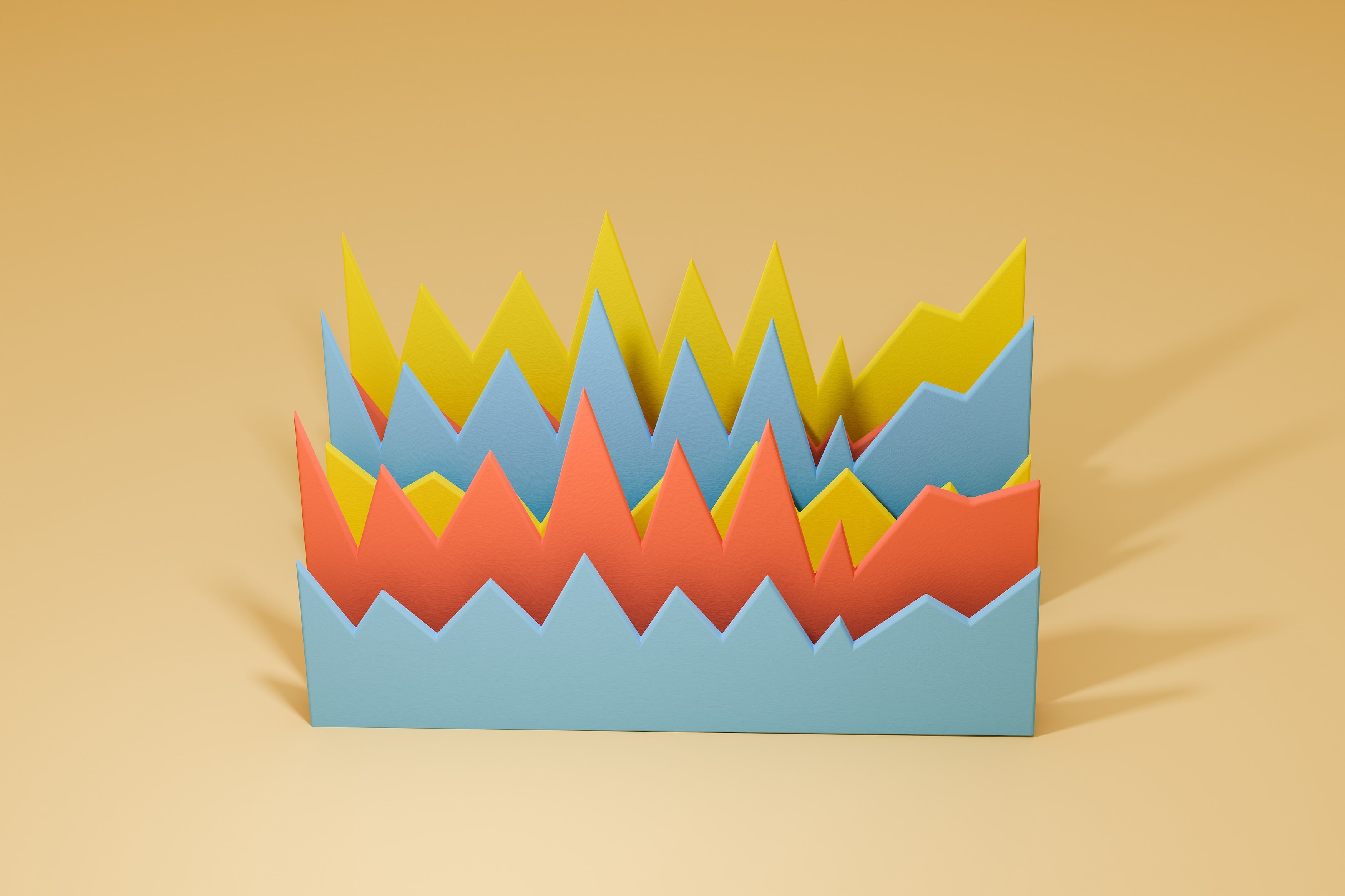 Cut-paper zigzag charts in blue, orange and yellow standing on a sand-coloured surface