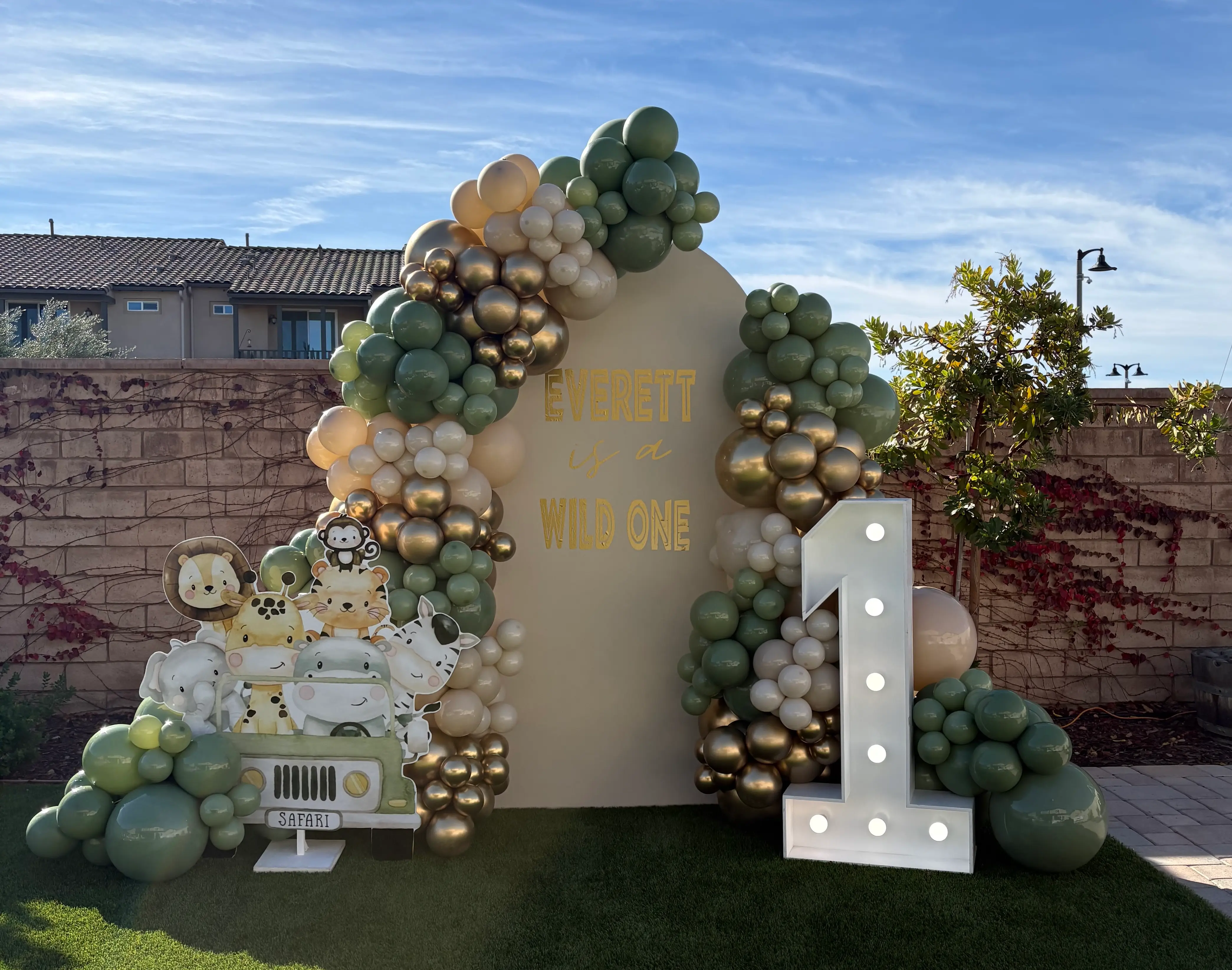 Boho safari first birthday setup with balloon arch, jungle animals decor and custom wild one backdrop in Inland Empire
